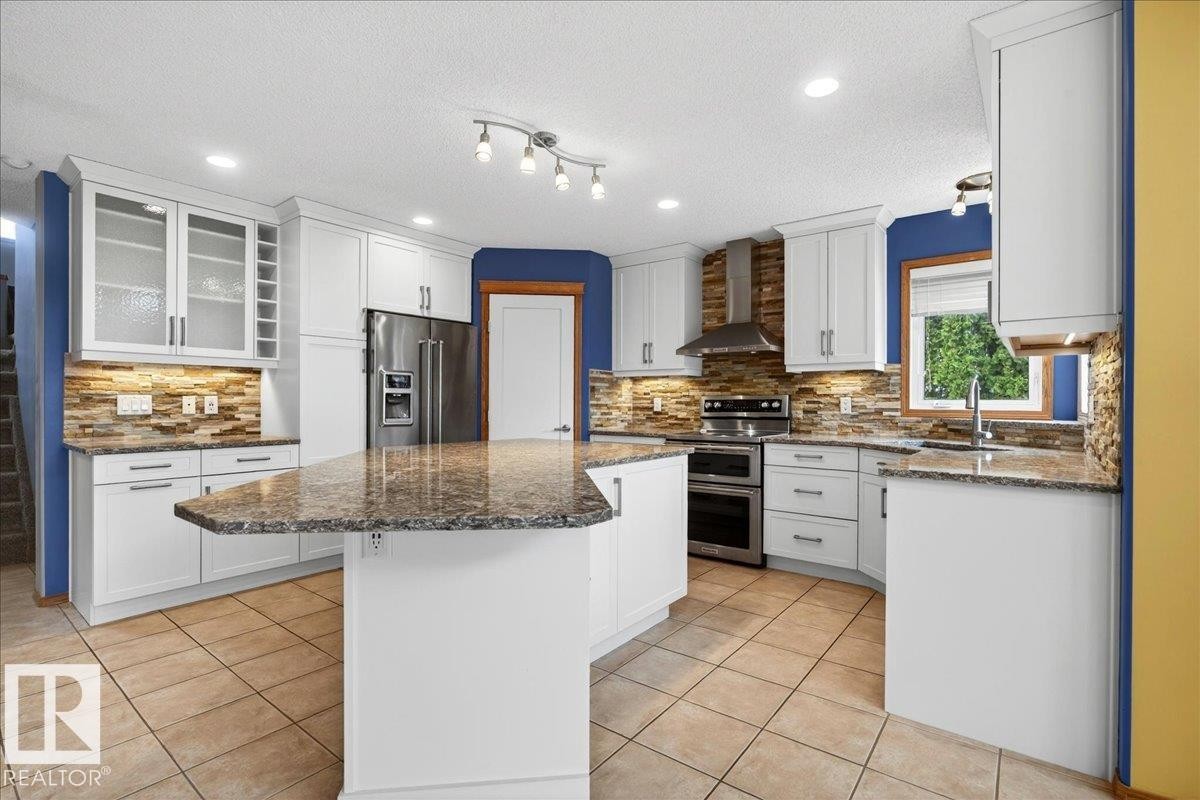 Contemporary kitchen featuring white cabinetry, stone-look countertops, and a stone-tiled backsplash - 11824 13 Avenue, Edmonton, AB - Indoor Photo Showing Kitchen With Upgraded Kitchen