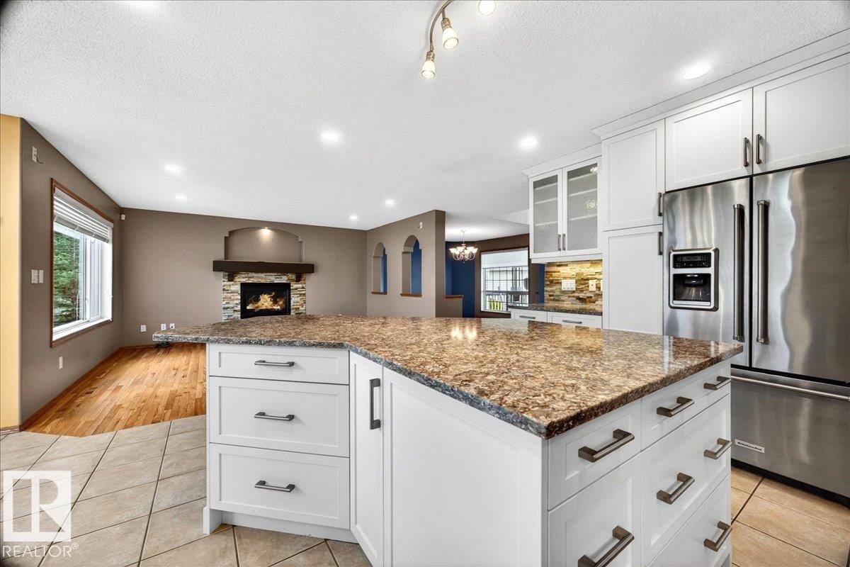 Kitchen island with a granite countertop, white cabinetry, and brushed nickel hardware - 11824 13 Avenue, Edmonton, AB - Indoor Photo Showing Kitchen With Upgraded Kitchen