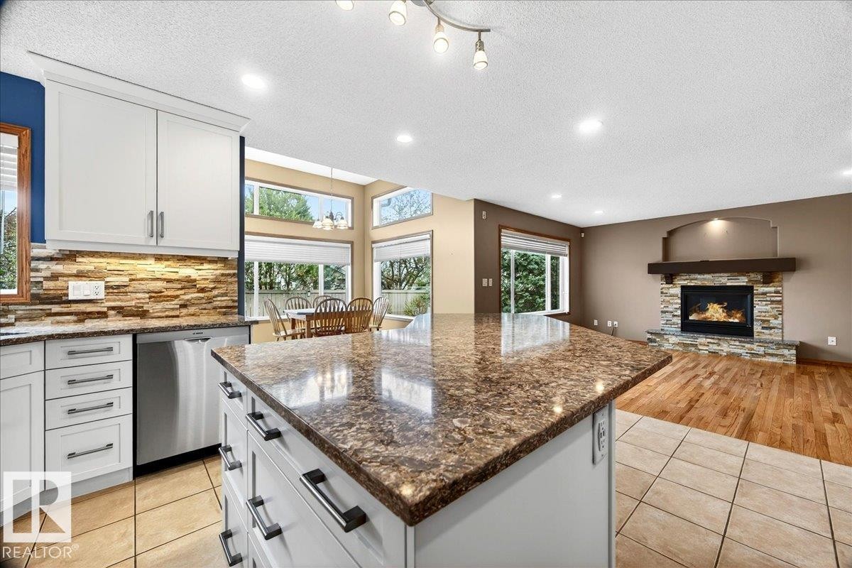 Kitchen island with a polished countertop and built-in cabinetry - 11824 13 Avenue, Edmonton, AB - Indoor Photo Showing Kitchen With Upgraded Kitchen
