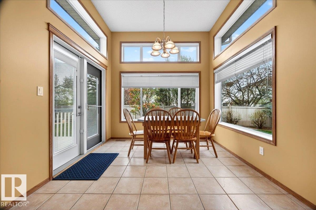 Dining area featuring expansive windows, transom windows, ceramic tile flooring, and a glass-paneled patio door with an integrated screen - 11824 13 Avenue, Edmonton, AB - Indoor