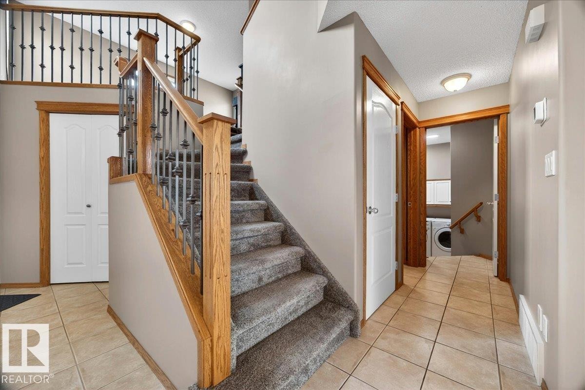 Foyer featuring a grand staircase with wood newel posts, handrails, and wrought iron balusters - 11824 13 Avenue, Edmonton, AB - Indoor Photo Showing Other Room