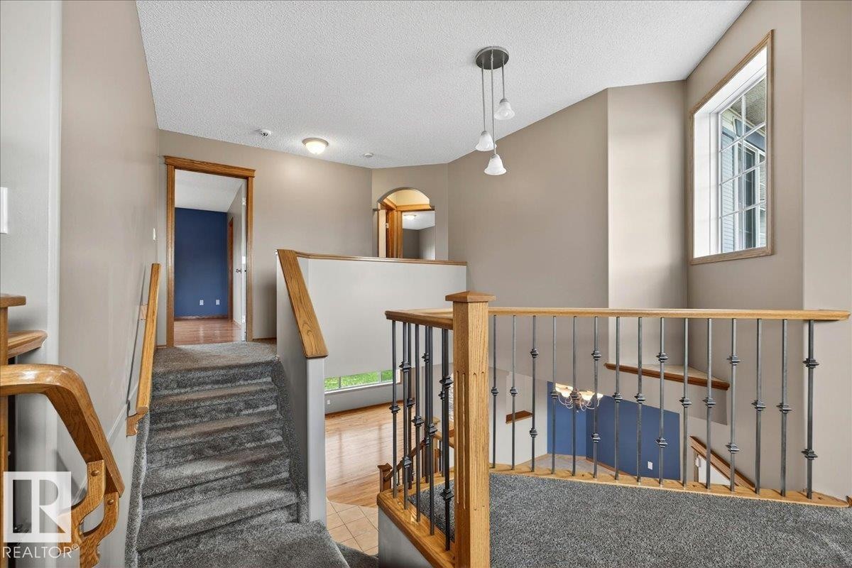Upper-level landing with carpeted stairs, wood railings, and wrought-iron balusters - 11824 13 Avenue, Edmonton, AB - Indoor Photo Showing Other Room