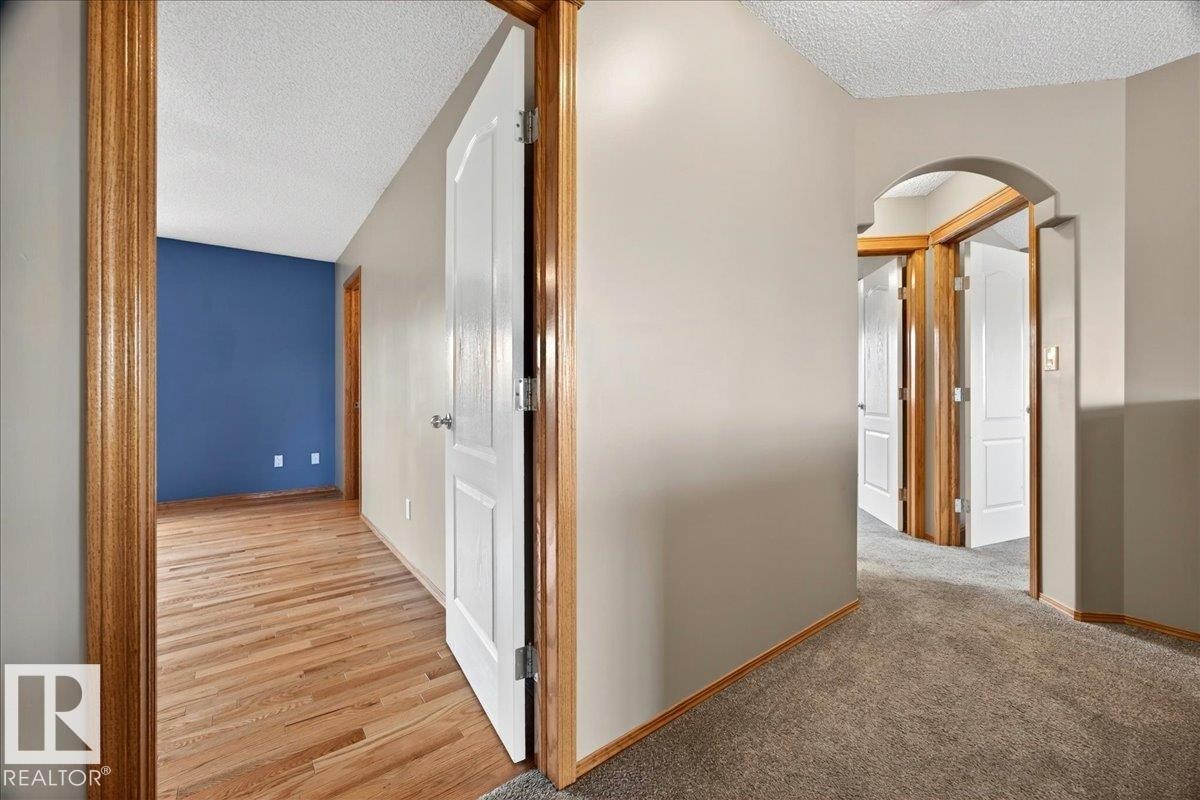 Hallway featuring neutral wall paint, wood-finish flooring, and a carpeted section - 11824 13 Avenue, Edmonton, AB - Indoor Photo Showing Other Room