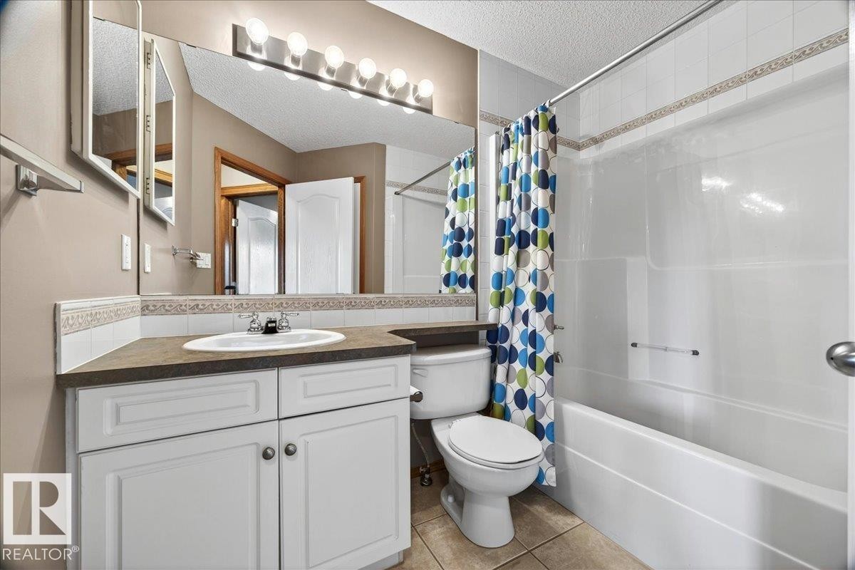 Bathroom featuring a white vanity with cabinet storage, a built-in sink, and a dark countertop - 11824 13 Avenue, Edmonton, AB - Indoor Photo Showing Bathroom
