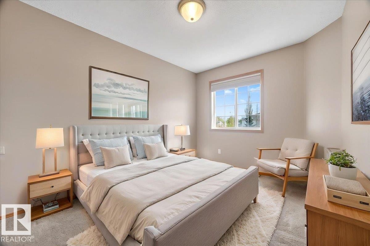 Bedroom featuring neutral wall paint, light-toned carpet flooring, a window with natural wood trim, and an overhead flush-mount light fixture - 11824 13 Avenue, Edmonton, AB - Indoor Photo Showing Bedroom