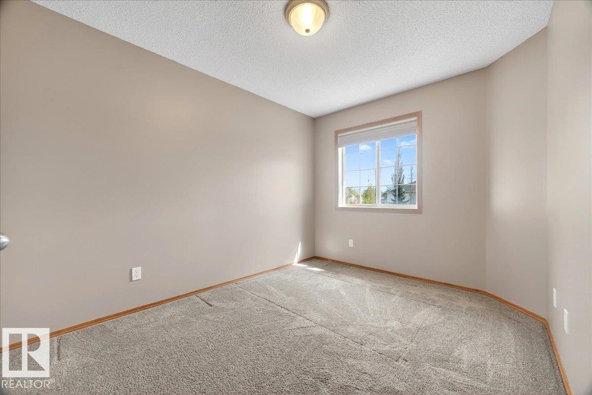 Neutral tone walls with light-toned carpeting and wood-finish baseboards - 11824 13 Avenue, Edmonton, AB - Indoor Photo Showing Other Room