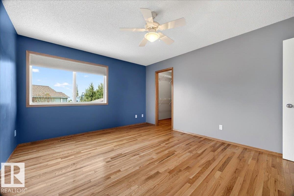 Spacious room featuring wood-finish flooring, a large window with wood trim, and a ceiling fan with integrated lighting - 11824 13 Avenue, Edmonton, AB - Indoor Photo Showing Other Room