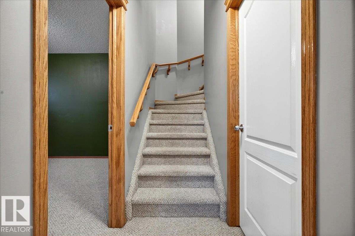 Carpeted staircase with wood-finish handrail and newel posts - 11824 13 Avenue, Edmonton, AB - Indoor Photo Showing Other Room