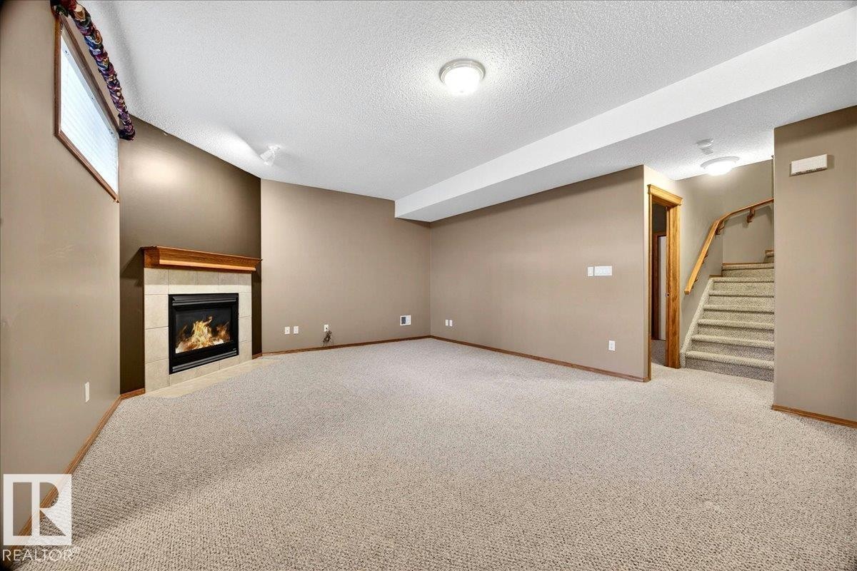 Spacious room featuring a corner fireplace with a tiled surround and wood mantel - 11824 13 Avenue, Edmonton, AB - Indoor With Fireplace