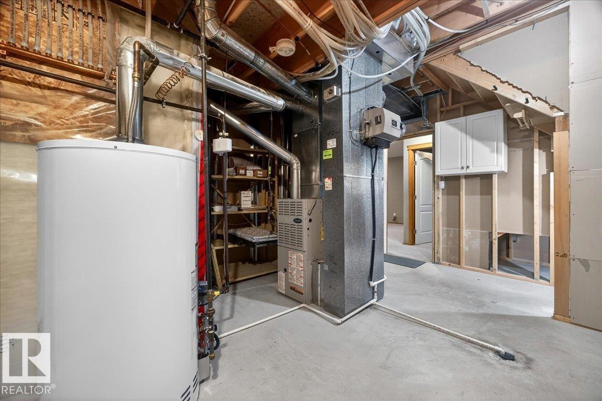 Dedicated utility area featuring a water heater, furnace, and exposed ductwork - 11824 13 Avenue, Edmonton, AB - Indoor Photo Showing Basement