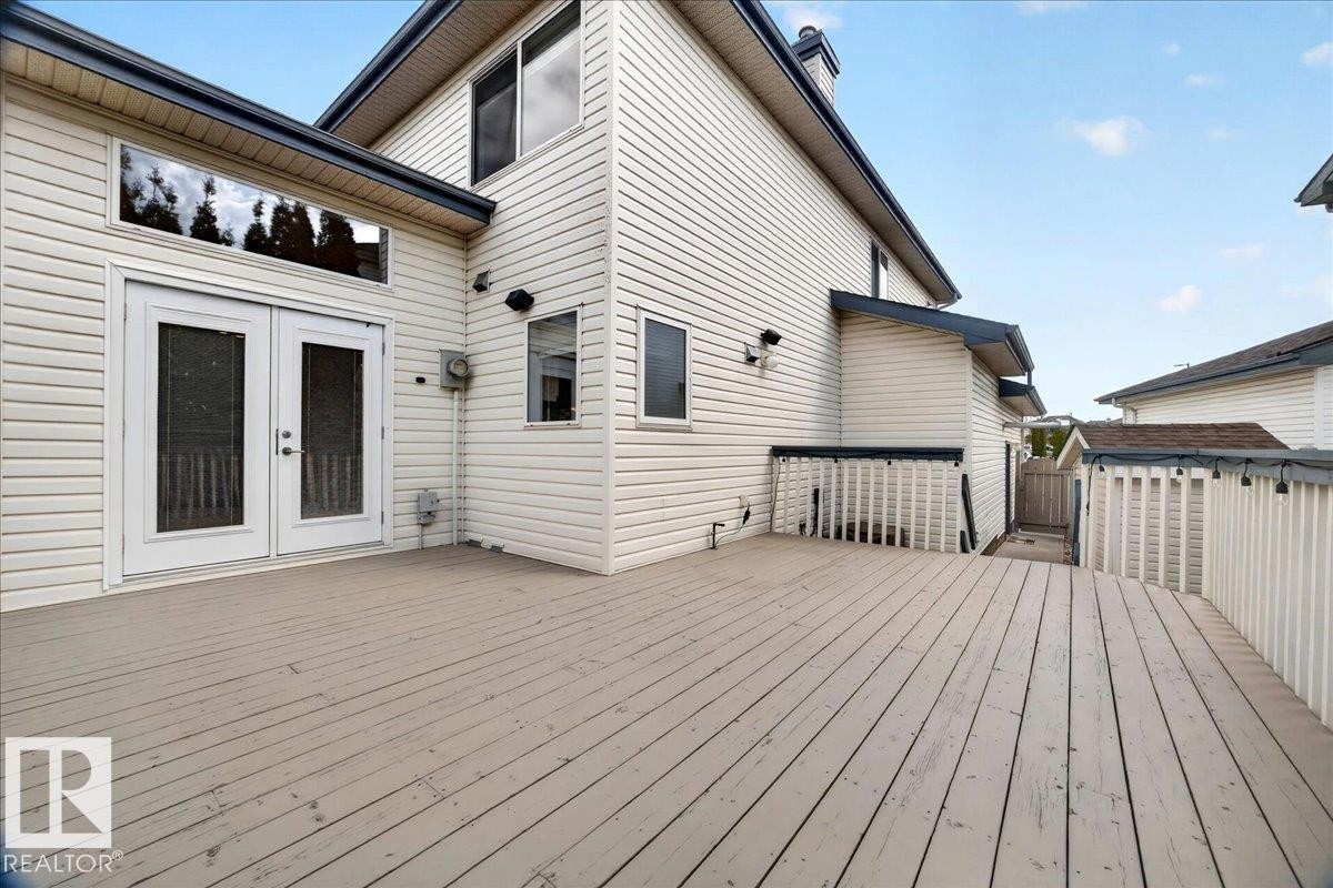 Expansive wood-finish deck with white railings and dual access points - 11824 13 Avenue, Edmonton, AB - Outdoor With Deck Patio Veranda With Exterior