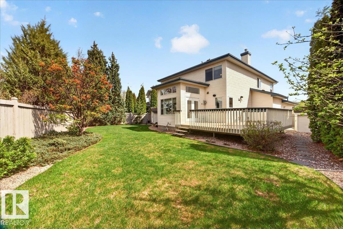 Expansive green lawn with established plantings, a full-length wooden deck, and a privacy fence - 11824 13 Avenue, Edmonton, AB - Outdoor With Deck Patio Veranda