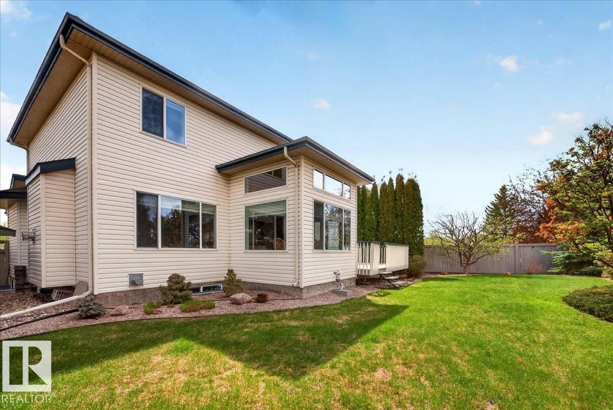 Rear exterior featuring light-toned horizontal siding, multiple windows, and a raised deck with white railing - 11824 13 Avenue, Edmonton, AB - Outdoor