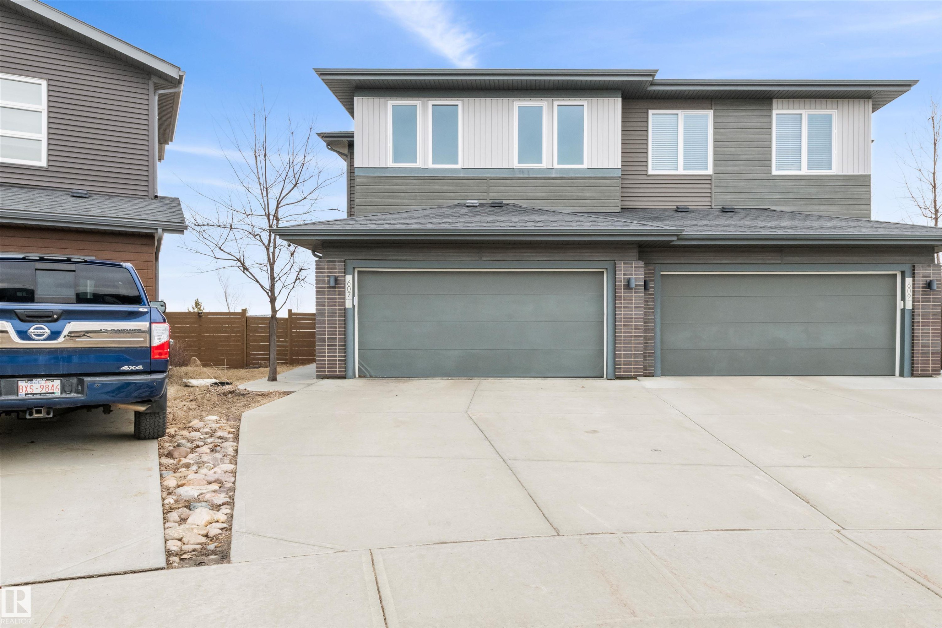 The property exterior features a contemporary design with dual garages, a paved driveway, and horizontal siding in varying shades - 607 40 Street Sw, Edmonton, AB - Outdoor