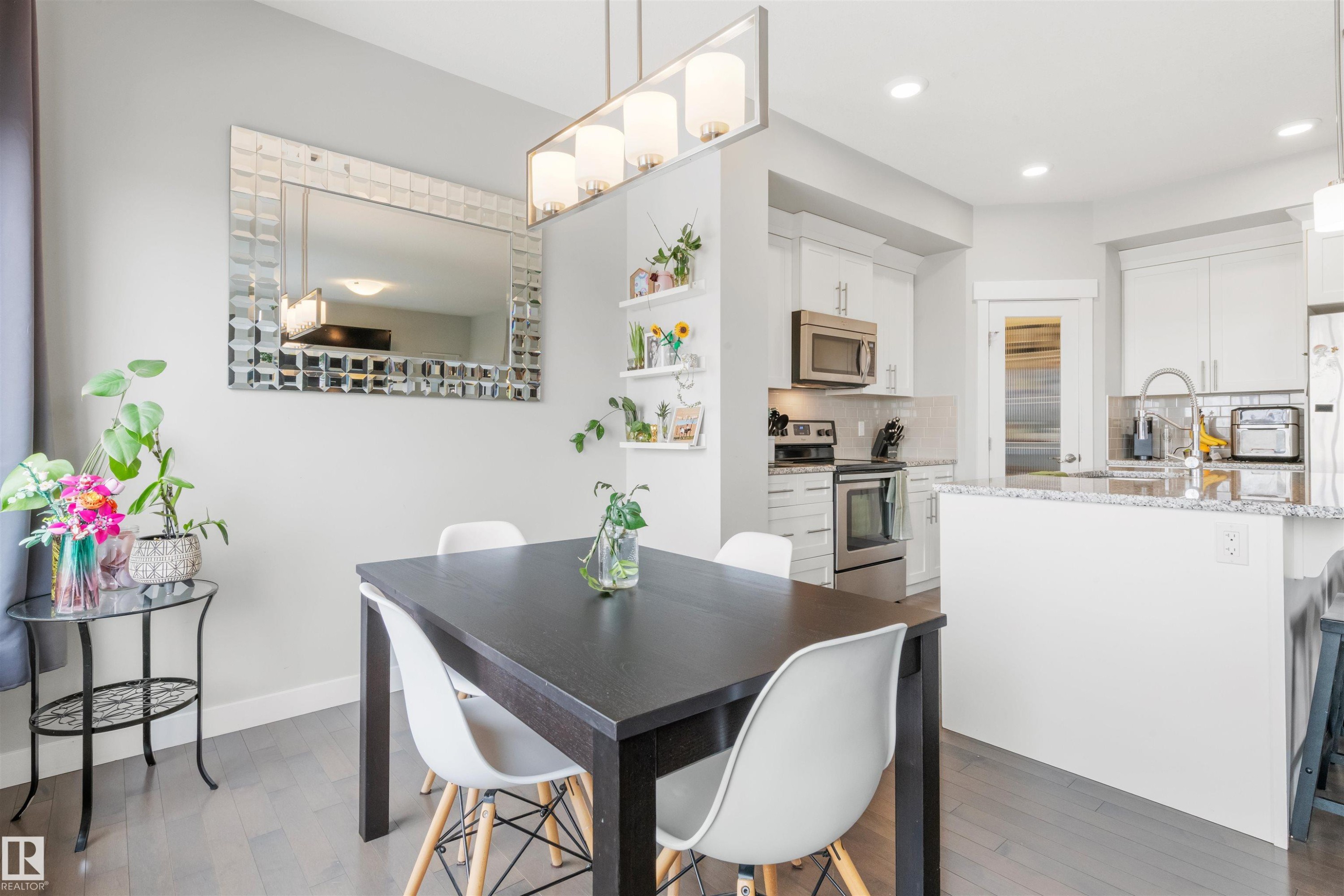Dining area featuring hardwood floors, a contemporary chandelier, and a decorative wall mirror - 607 40 Street Sw, Edmonton, AB - Indoor