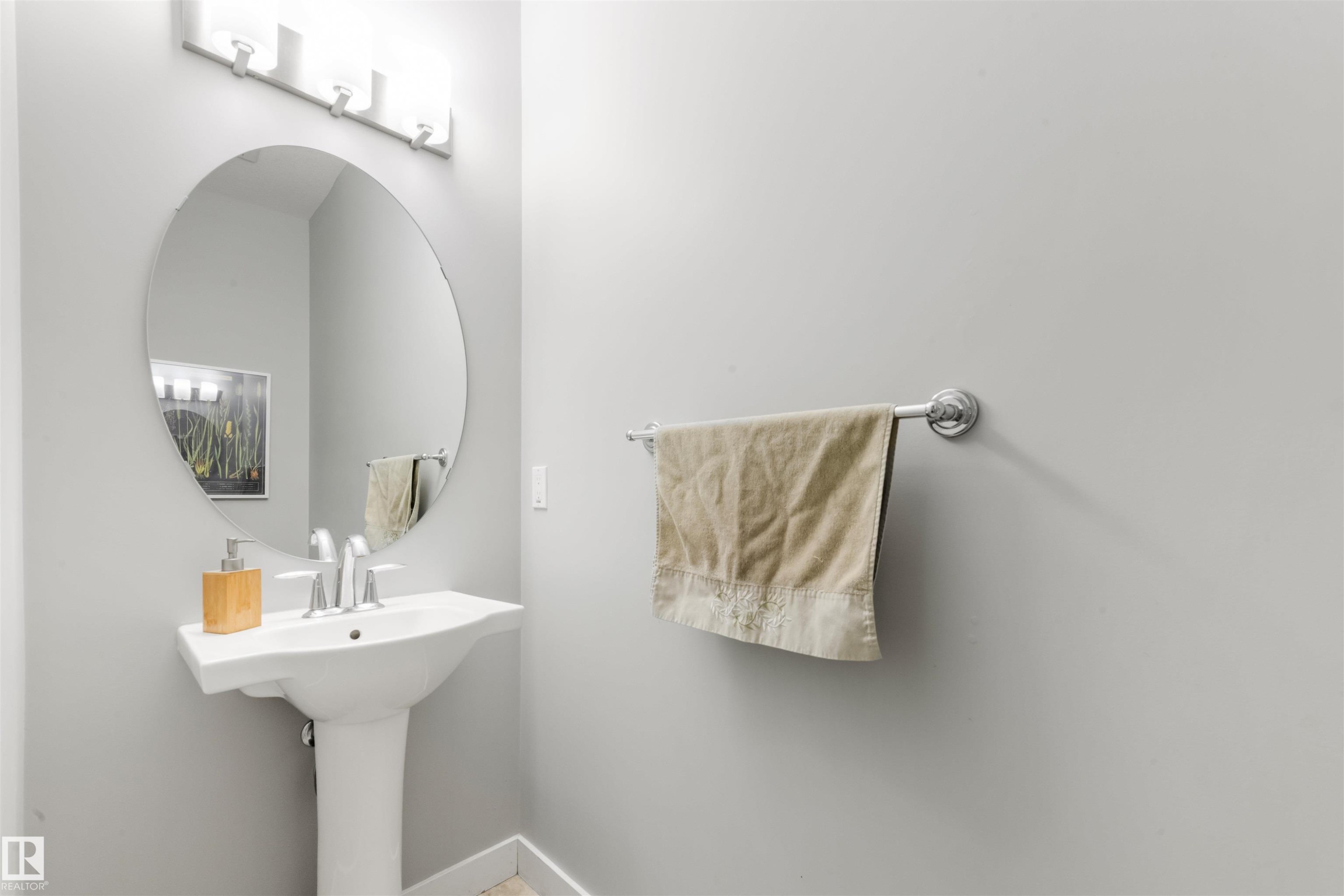 Bathroom featuring a pedestal sink, a circular mirror, and a chrome towel bar - 607 40 Street Sw, Edmonton, AB - Indoor Photo Showing Bathroom
