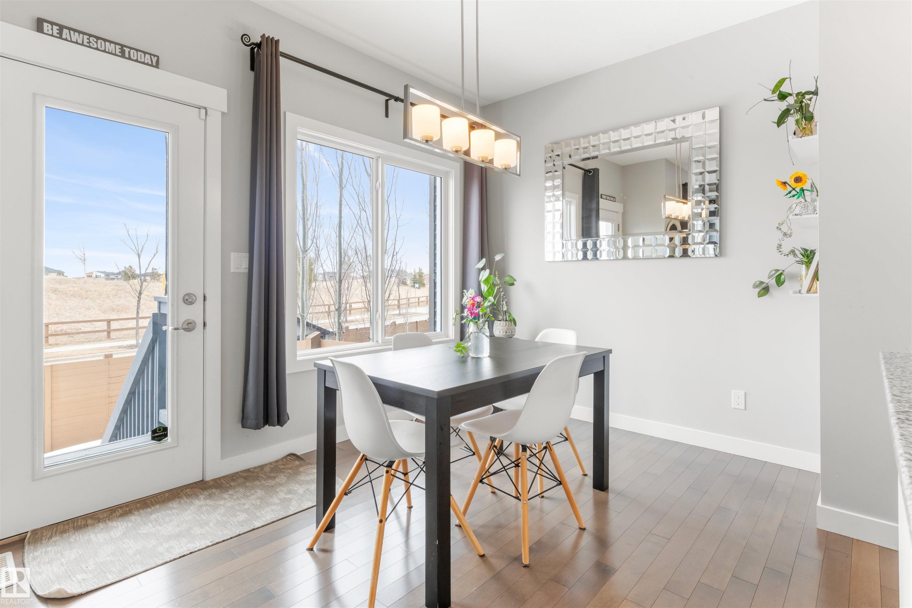 Dining area featuring hardwood floors, a modern chandelier, and a large window providing natural light - 607 40 Street Sw, Edmonton, AB - Indoor Photo Showing Dining Room