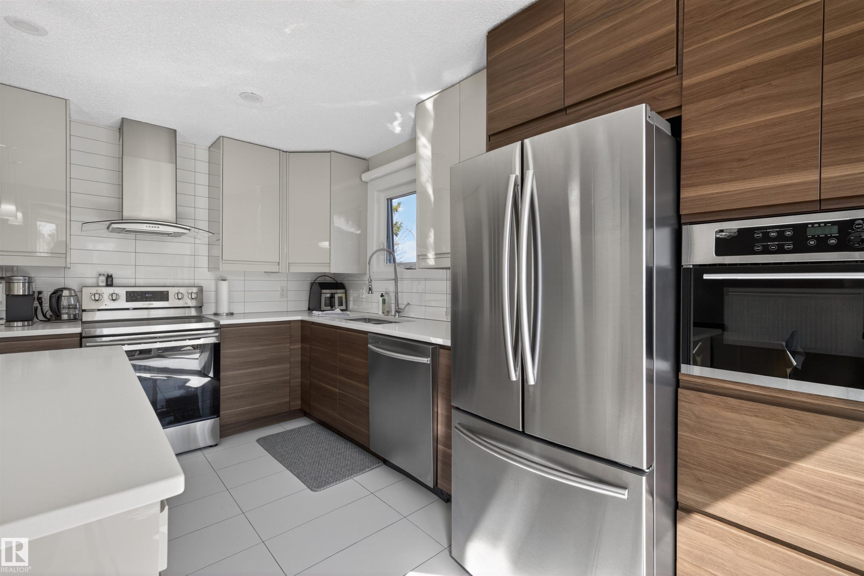 Modern kitchen featuring stainless steel appliances, two-tone cabinetry, white subway tile backsplash, white countertops, and recessed lighting - 15251 88A Street, Edmonton, AB - Indoor Photo Showing Kitchen
