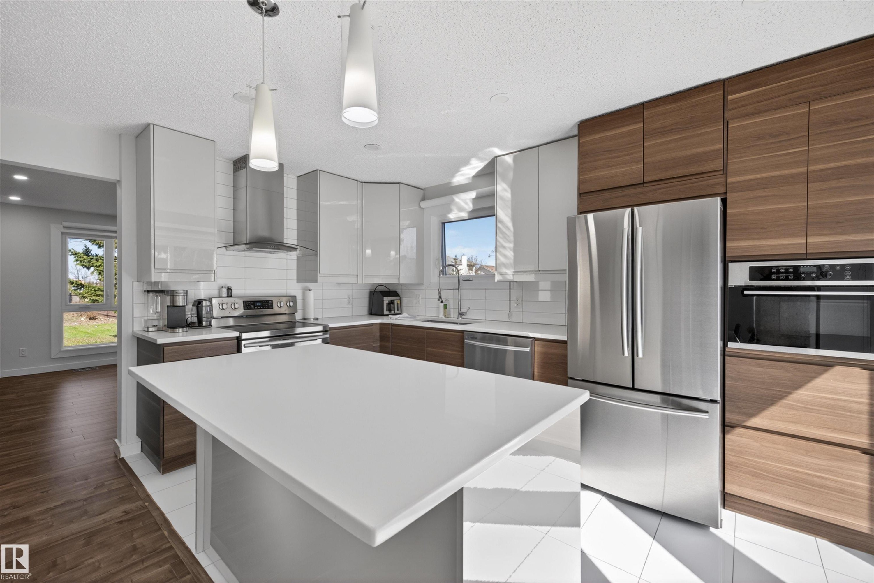 Kitchen featuring a large central island with a white countertop, two-tone cabinetry, stainless steel appliances, a subway tile backsplash, and recessed lighting - 15251 88A Street, Edmonton, AB - Indoor Photo Showing Kitchen With Upgraded Kitchen