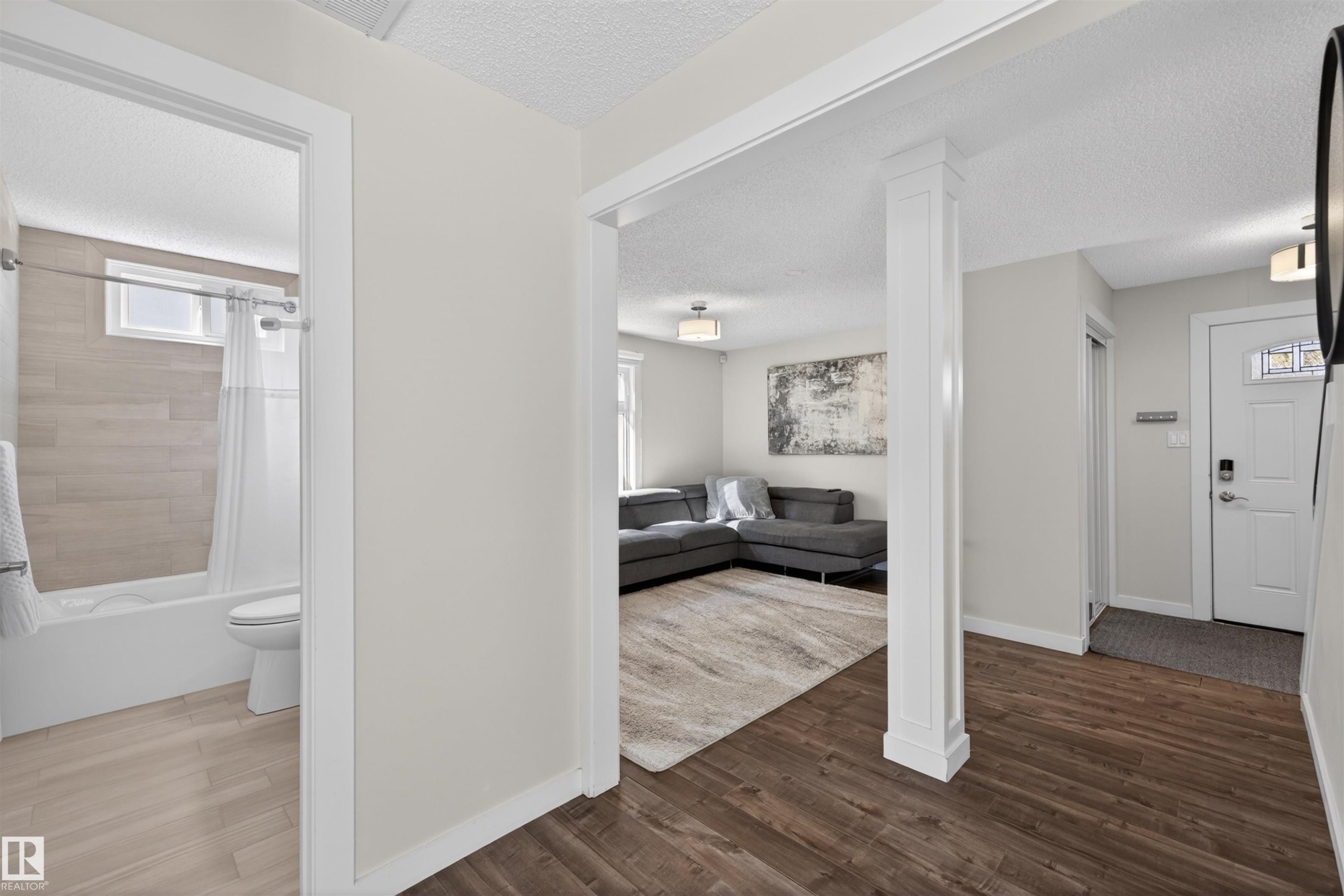 Open-concept living area featuring rich wood-finish flooring, white trim, and light wall tones - 15251 88A Street, Edmonton, AB - Indoor Photo Showing Other Room