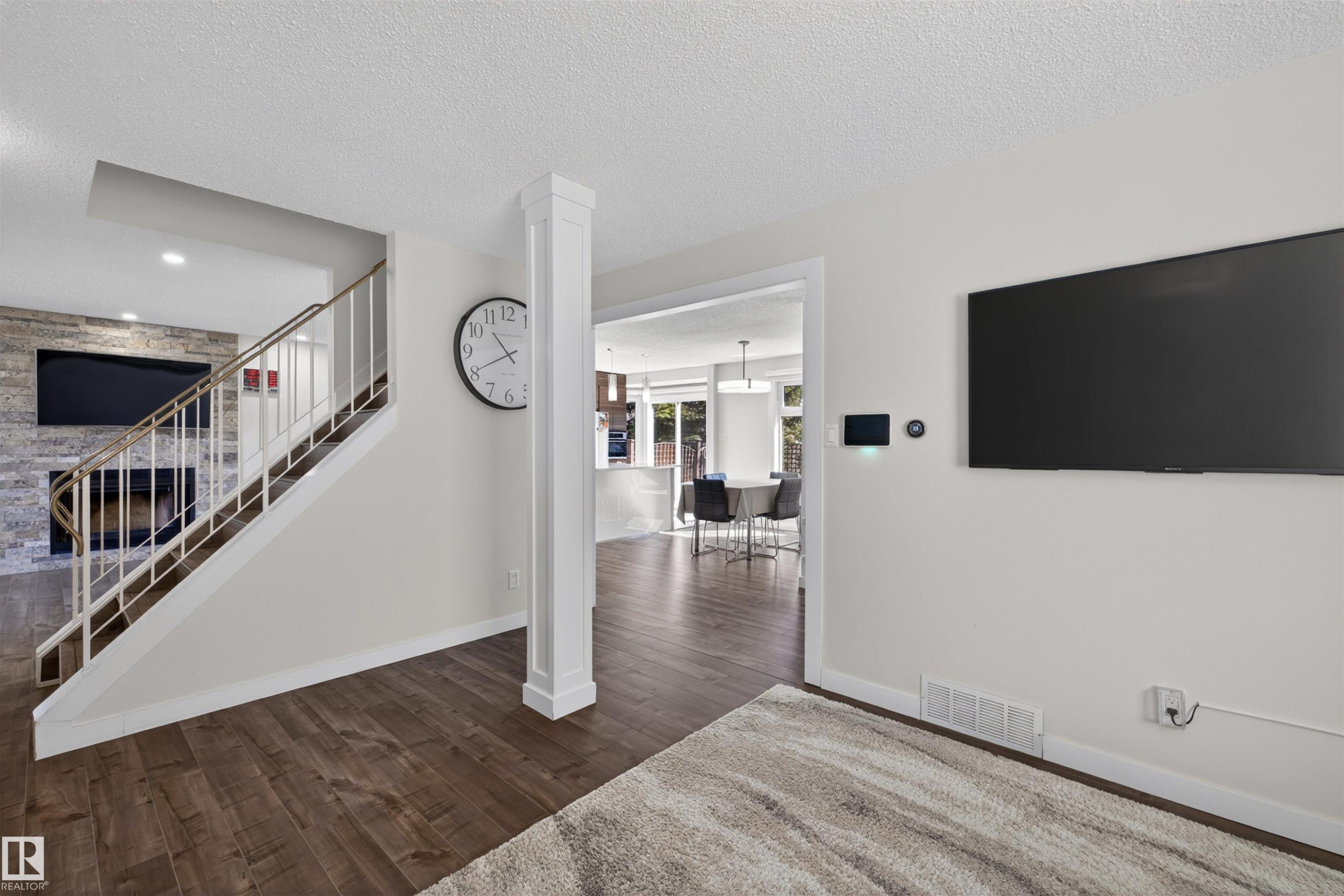 Wood-finish flooring throughout, featuring a staircase with white risers and metal balusters - 15251 88A Street, Edmonton, AB - Indoor Photo Showing Other Room