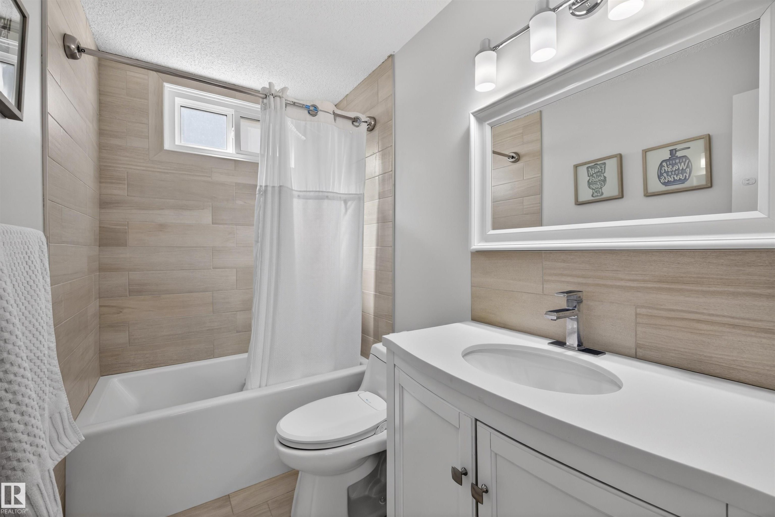 Bright bathroom featuring a white vanity with integrated sink, chrome faucet, and a large framed mirror - 15251 88A Street, Edmonton, AB - Indoor Photo Showing Bathroom