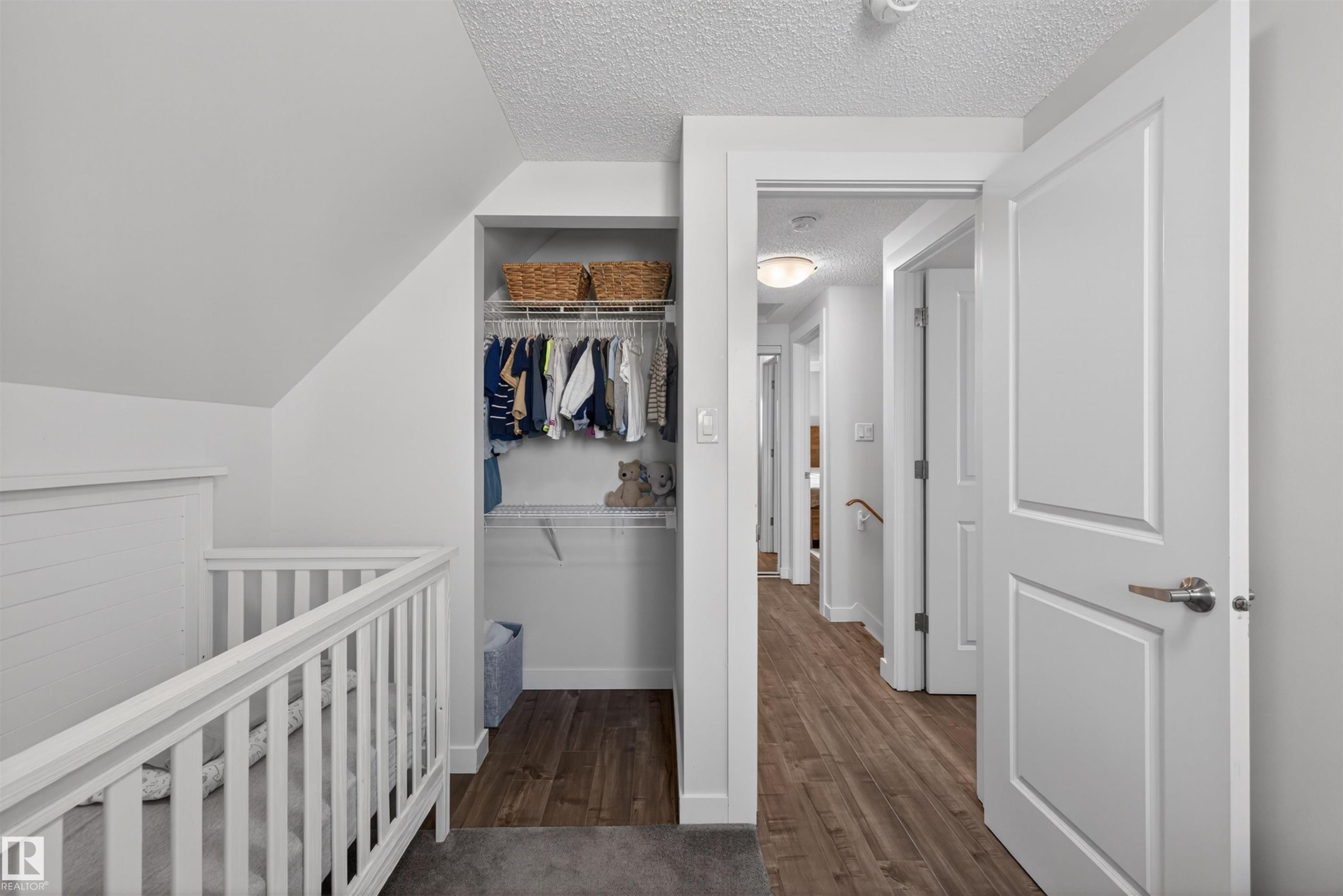 Bedroom featuring sloped ceilings, wire shelving closet, and wood-finish flooring - 15251 88A Street, Edmonton, AB - Indoor Photo Showing Other Room