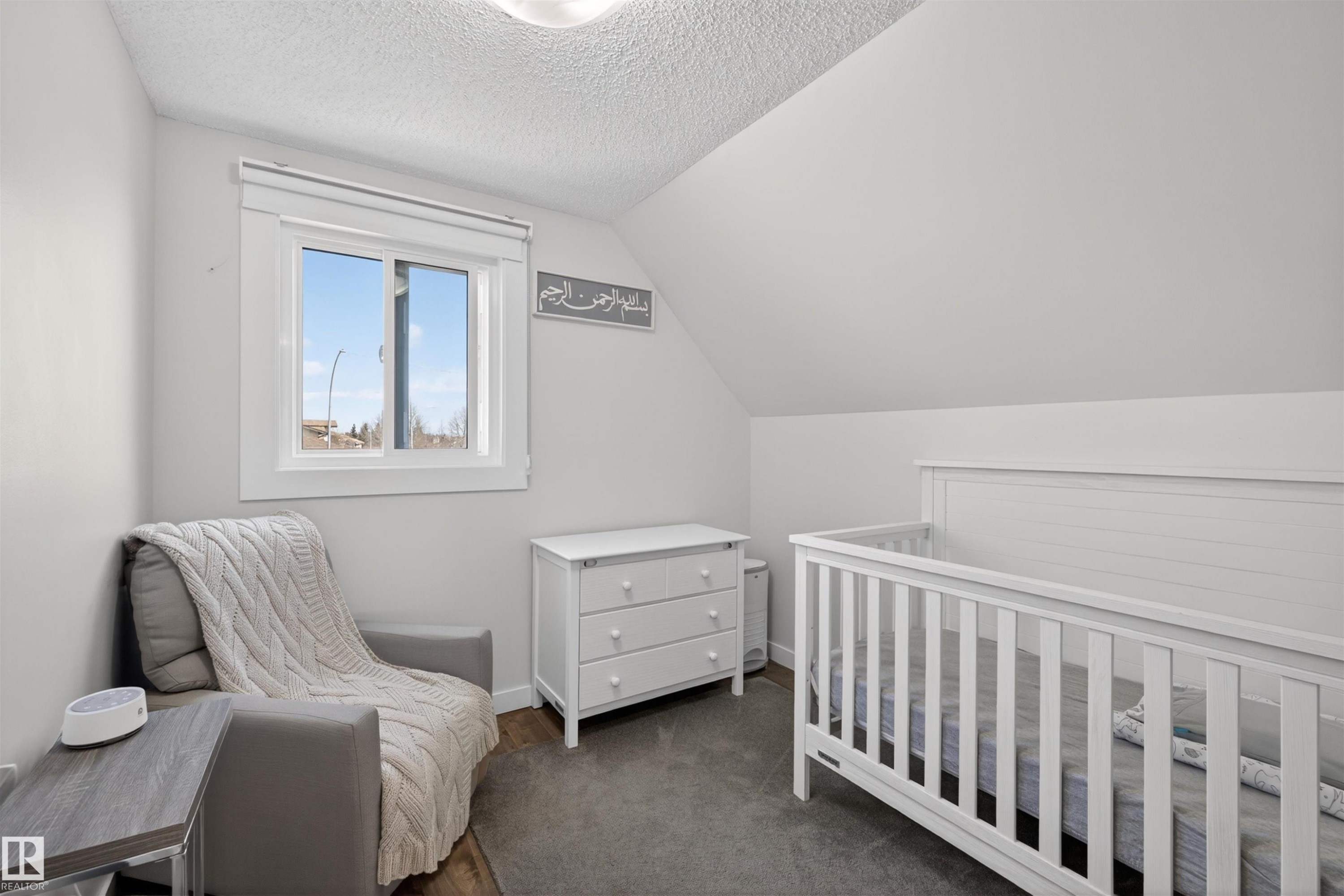 Bedroom featuring a window with white trim, wood-finish flooring, and a sloped ceiling - 15251 88A Street, Edmonton, AB - Indoor Photo Showing Bedroom