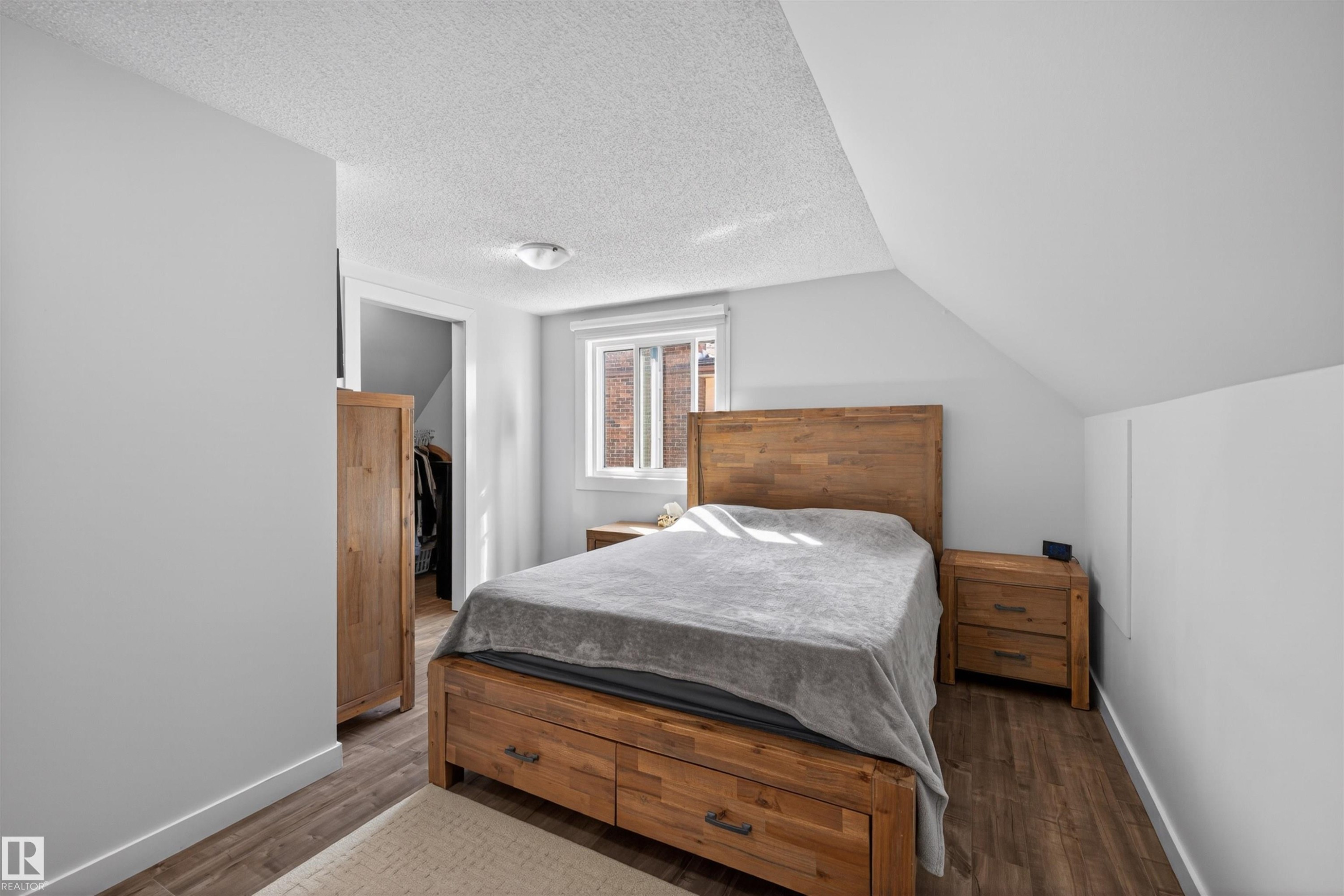 Bedroom featuring wood-finish flooring, a window with a roller shade, and an open closet - 15251 88A Street, Edmonton, AB - Indoor Photo Showing Bedroom