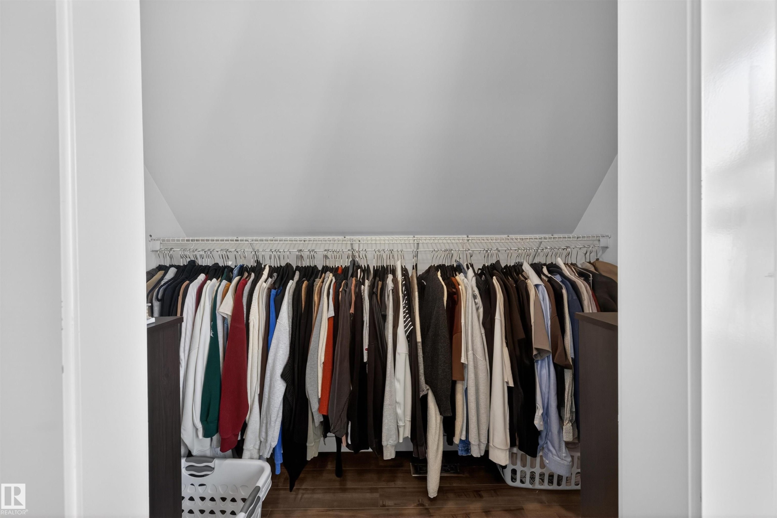 Wardrobe closet featuring a sloped ceiling, wood-finish flooring, and a full-width wire shelving system - 15251 88A Street, Edmonton, AB - Indoor With Storage