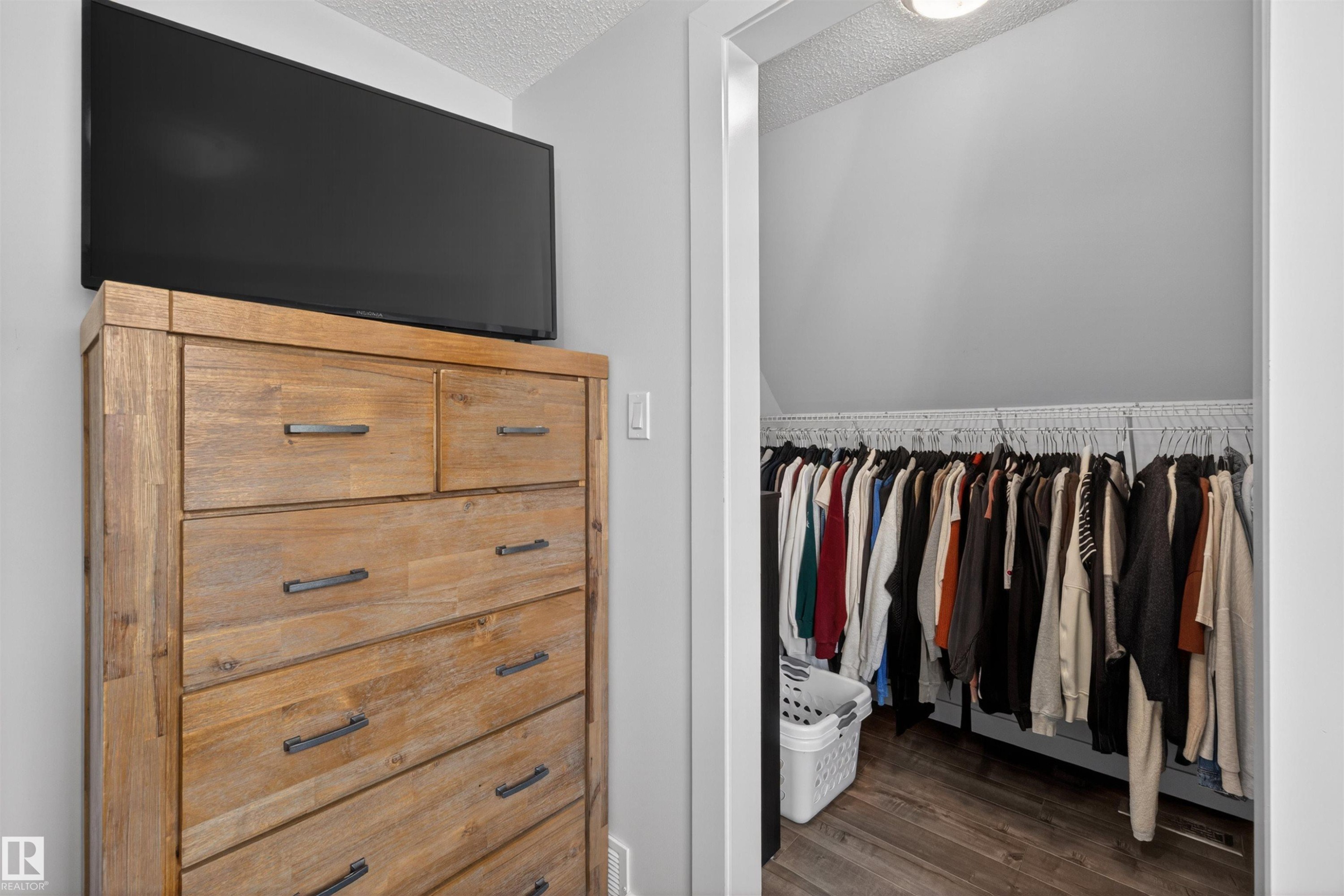 Walk-in closet featuring wood-finish flooring and ample hanging space - 15251 88A Street, Edmonton, AB - Indoor