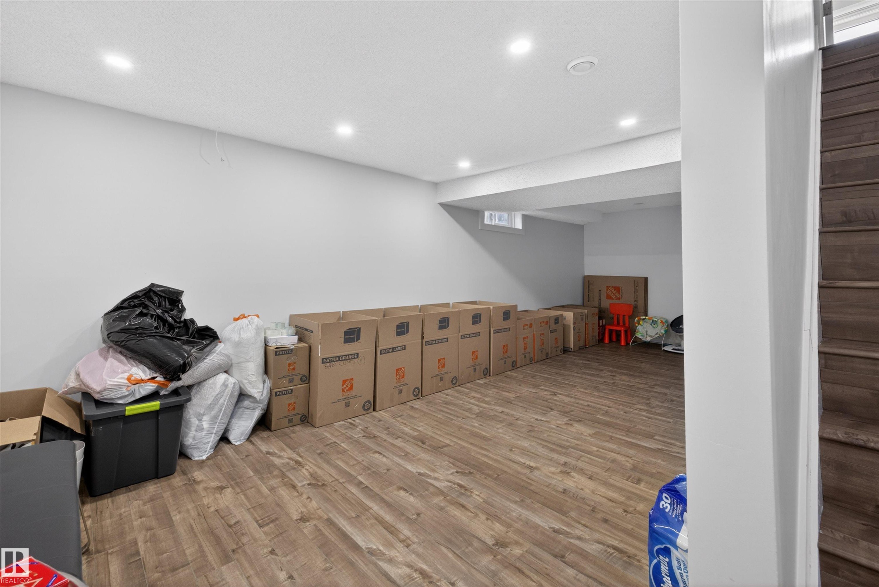 Lower level space featuring wood-finish flooring, recessed lighting, white walls, and a window well - 15251 88A Street, Edmonton, AB - Indoor