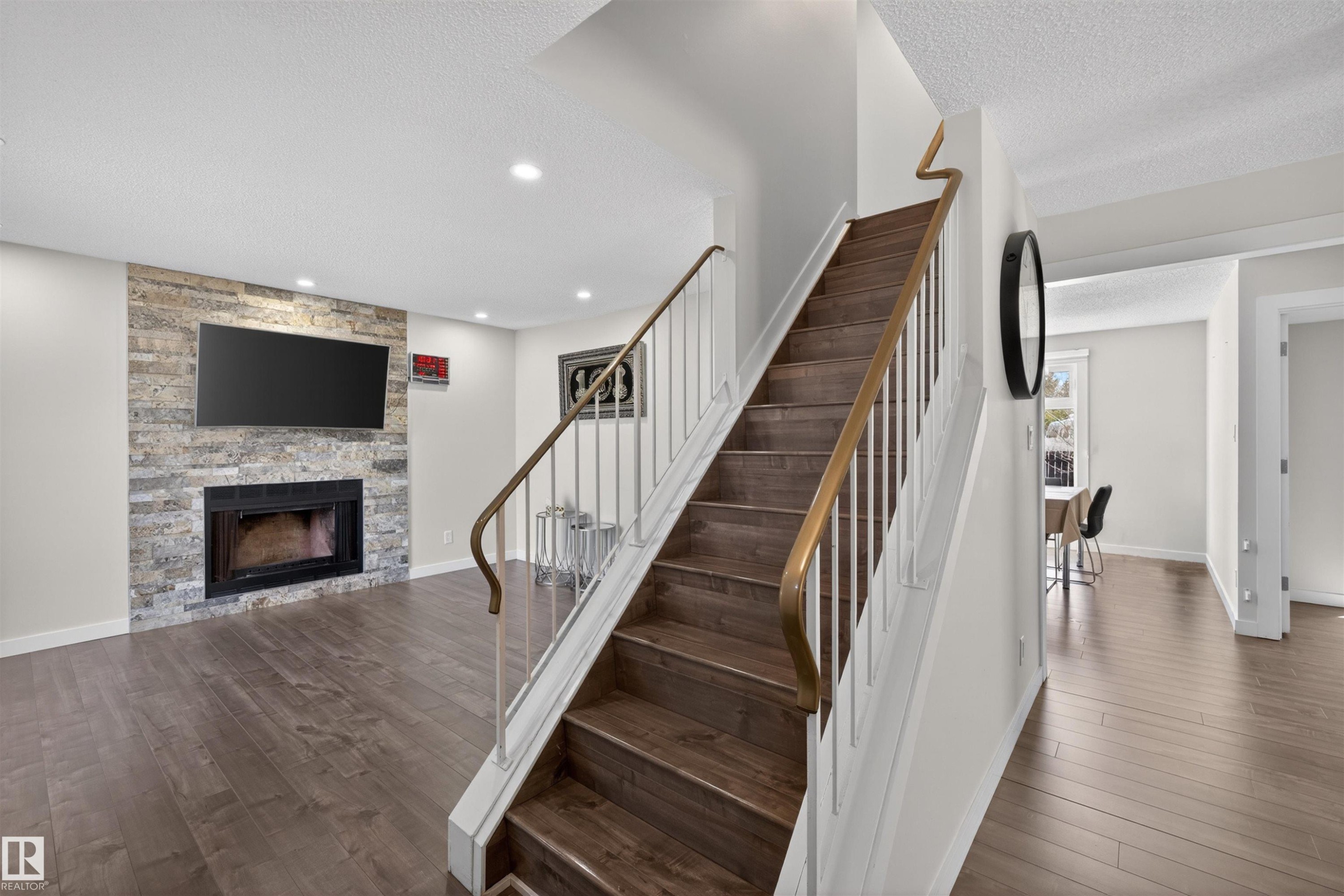 Staircase featuring wood-finish treads, a contrasting white and brass railing, and recessed lighting - 15251 88A Street, Edmonton, AB - Indoor With Fireplace