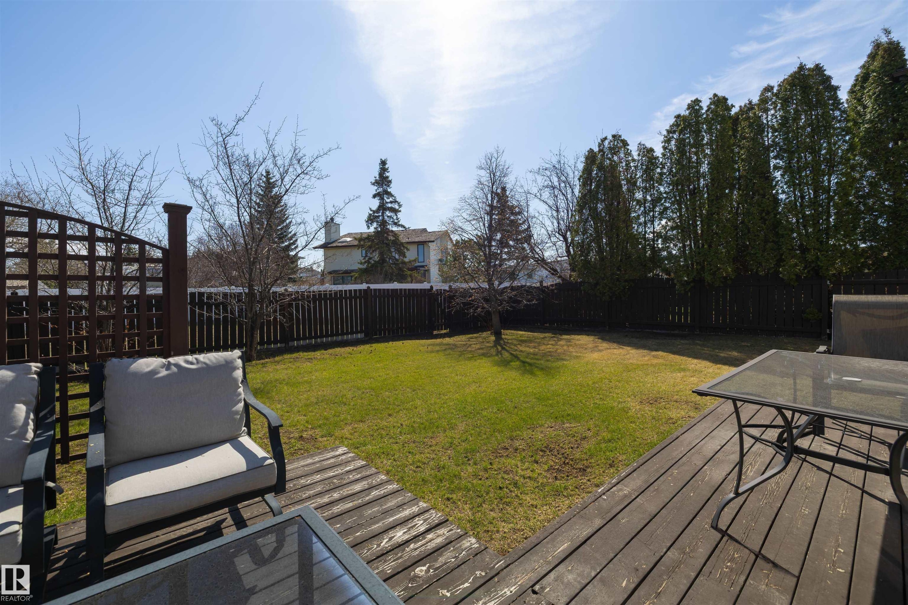 Expansive backyard featuring a dark wood-finish deck, a manicured lawn, and a privacy fence - 15251 88A Street, Edmonton, AB - Outdoor With Deck Patio Veranda With Backyard