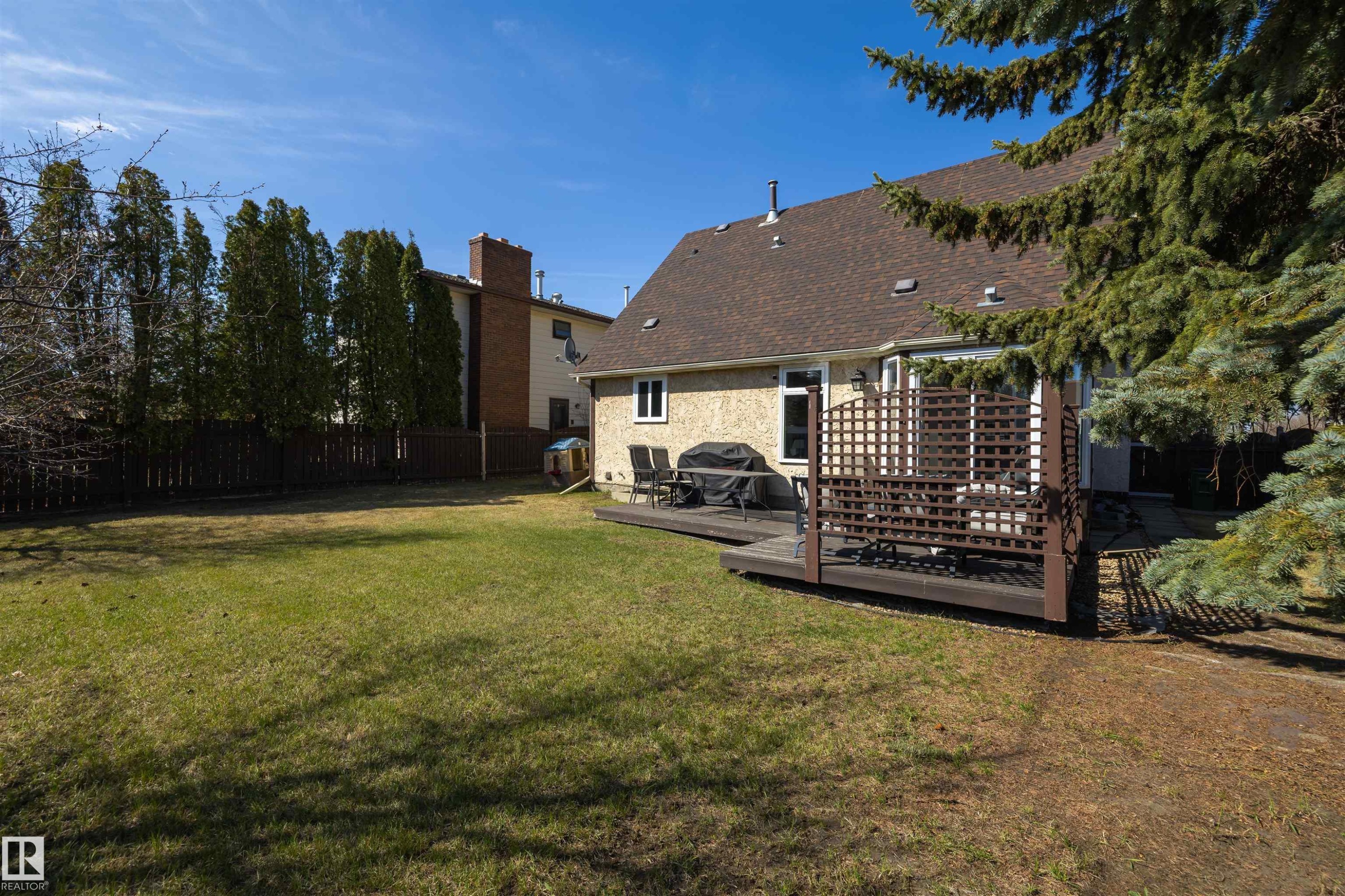 Expansive green lawn with a dark wood deck featuring privacy lattice - 15251 88A Street, Edmonton, AB - Outdoor