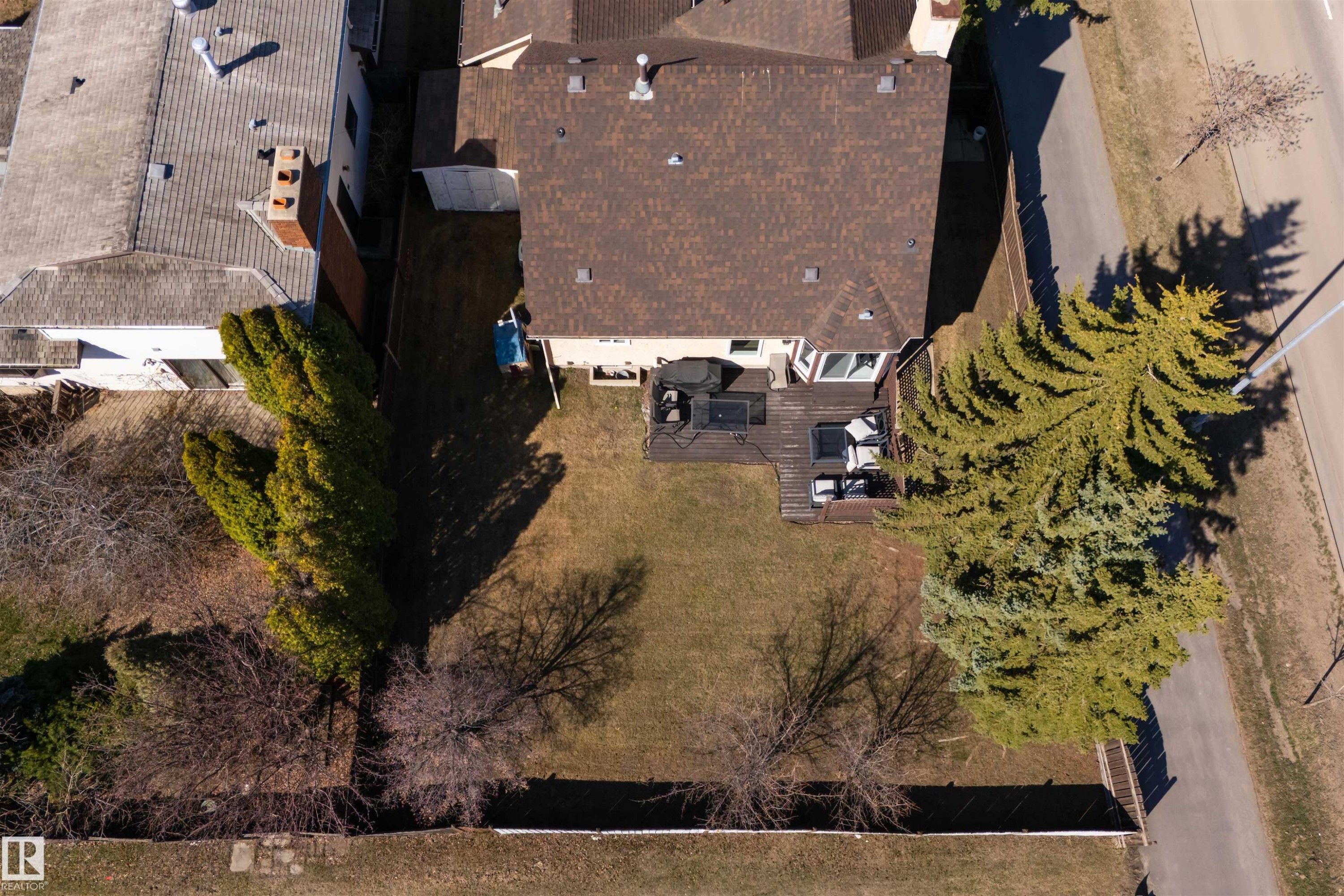Spacious backyard featuring a multi-level wood-finish deck, mature evergreen trees, and a substantial lawn area - 15251 88A Street, Edmonton, AB - Outdoor