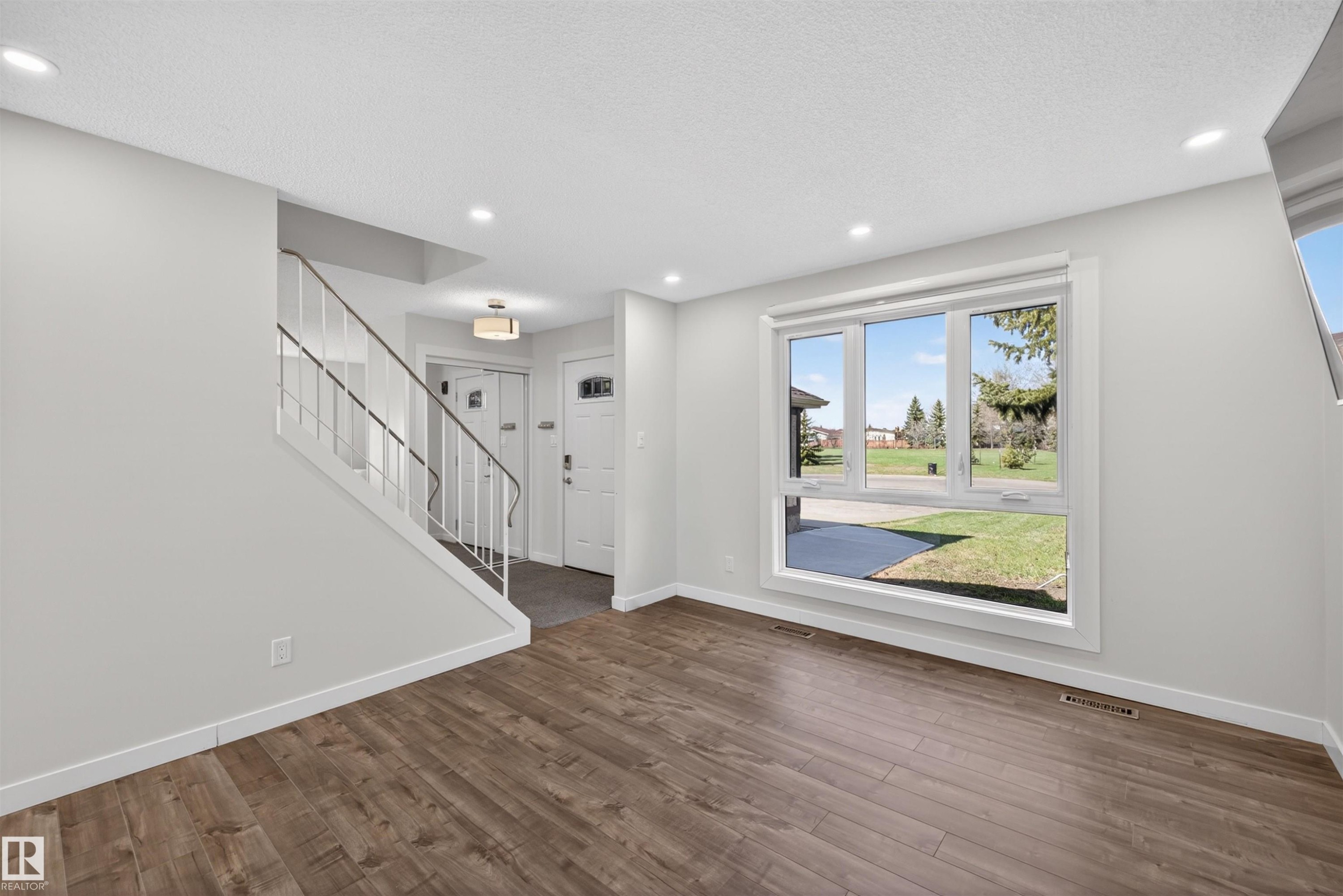 Spacious interior featuring wood-finish flooring, recessed ceiling lighting, and a large multi-pane window - 15251 88A Street, Edmonton, AB - Indoor Photo Showing Other Room