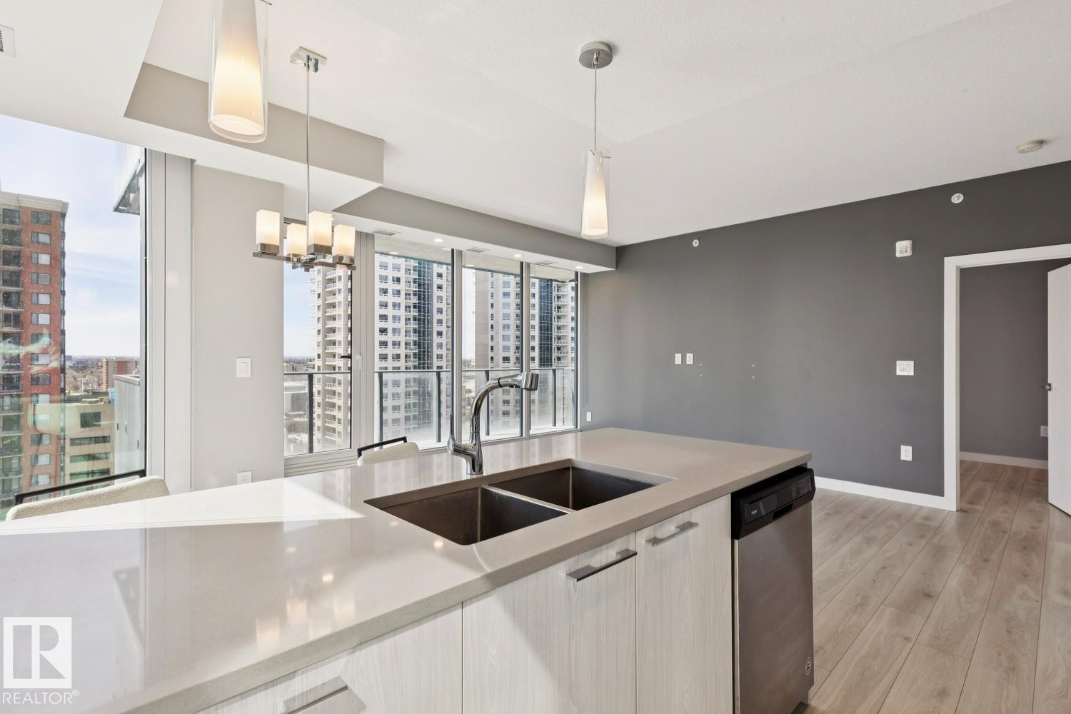 Modern kitchen island featuring a double-basin sink and integrated stainless steel dishwasher - #1601 10180 103 St Nw, Edmonton, AB - Indoor Photo Showing Kitchen With Double Sink