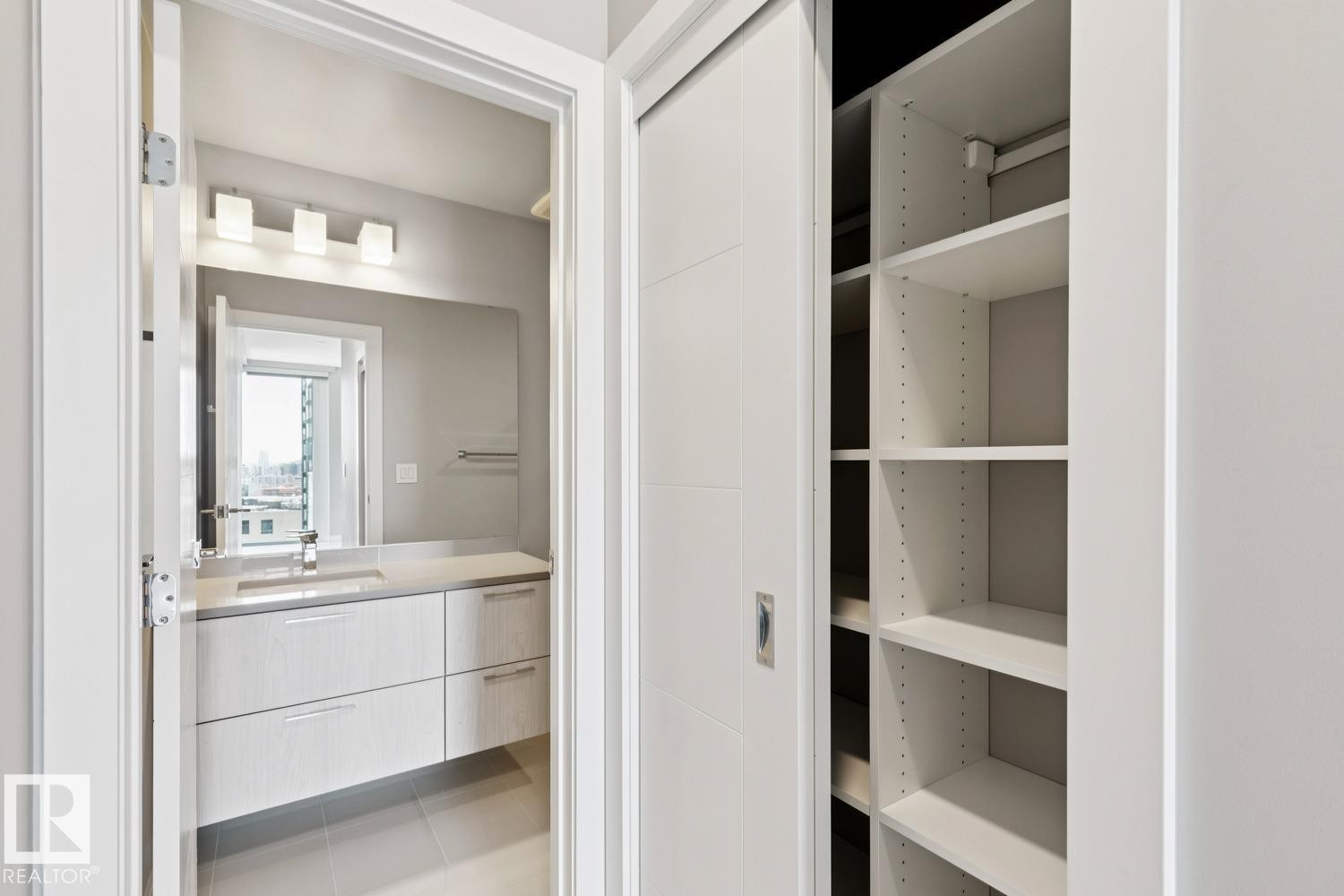 Integrated custom closet system featuring adjustable shelving - #1601 10180 103 St Nw, Edmonton, AB - Indoor Photo Showing Bathroom