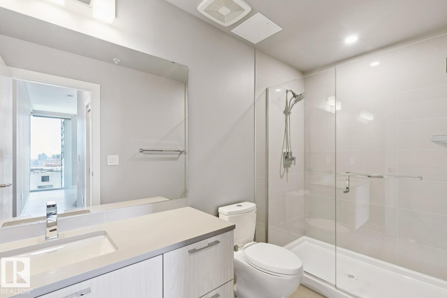Contemporary bathroom featuring a spacious glass-enclosed shower, a vanity with an integrated sink and chrome faucet, and a large mirror - #1601 10180 103 St Nw, Edmonton, AB - Indoor Photo Showing Bathroom