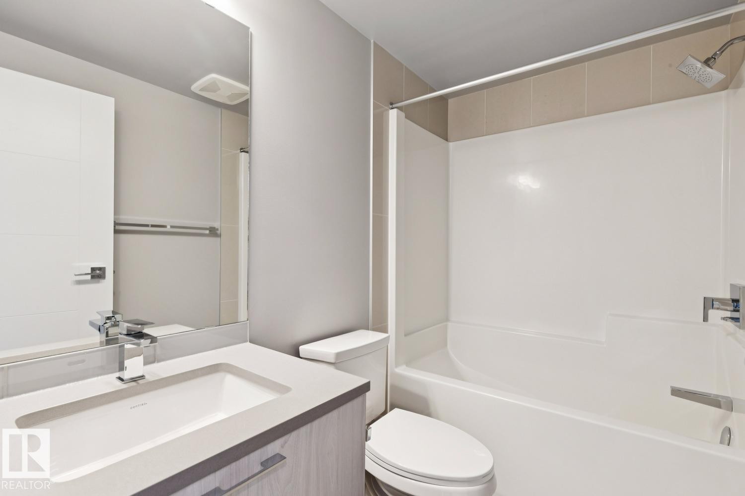 Bathroom featuring a white integrated sink with a chrome faucet, light wood-finish vanity with chrome pulls, and a large wall-mounted mirror - #1601 10180 103 St Nw, Edmonton, AB - Indoor Photo Showing Bathroom
