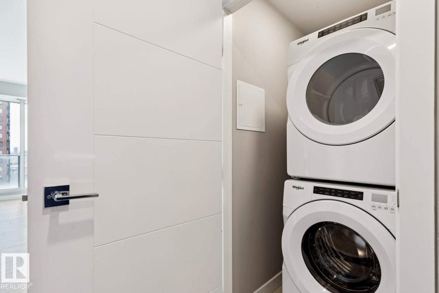 Dedicated laundry closet featuring a stacked white washer and dryer unit - #1601 10180 103 St Nw, Edmonton, AB - Indoor Photo Showing Laundry Room