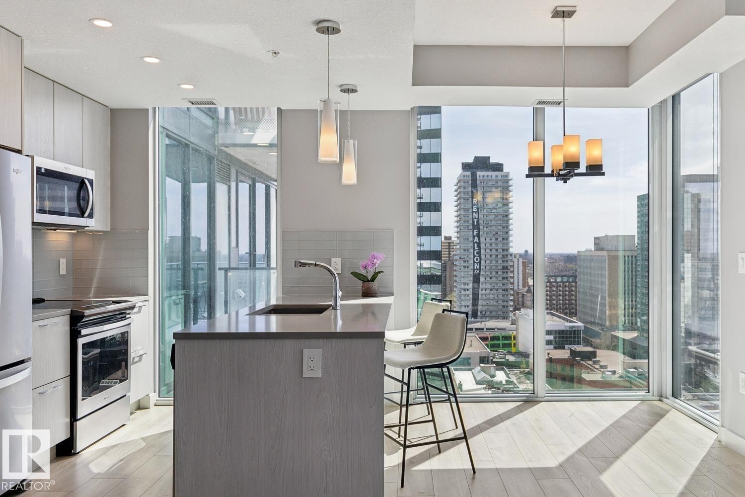 Modern kitchen featuring light wood-finish flooring and floor-to-ceiling windows - #1601 10180 103 St Nw, Edmonton, AB - Indoor Photo Showing Kitchen With Upgraded Kitchen
