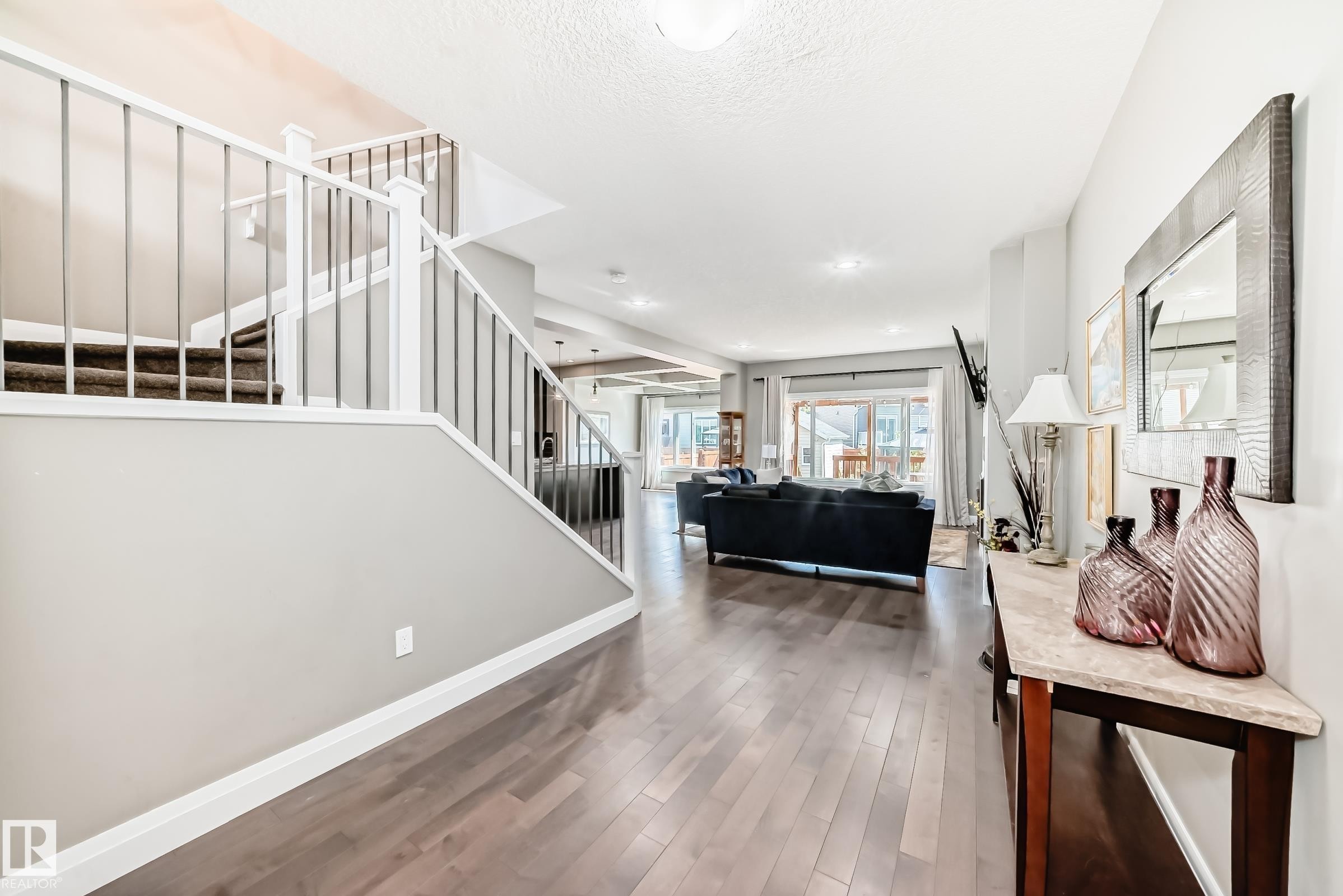 Foyer featuring wood-finish flooring, a contemporary staircase with metal balusters, and a console table with a stone countertop - 4155 Charles Link, Edmonton, AB - Indoor Photo Showing Other Room