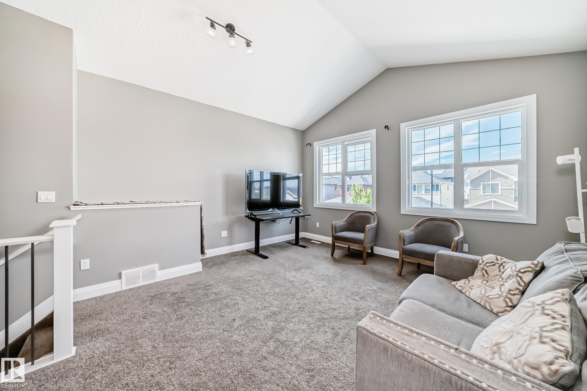 Spacious common area featuring vaulted ceilings, track lighting, and gray carpeting - 4155 Charles Link, Edmonton, AB - Indoor