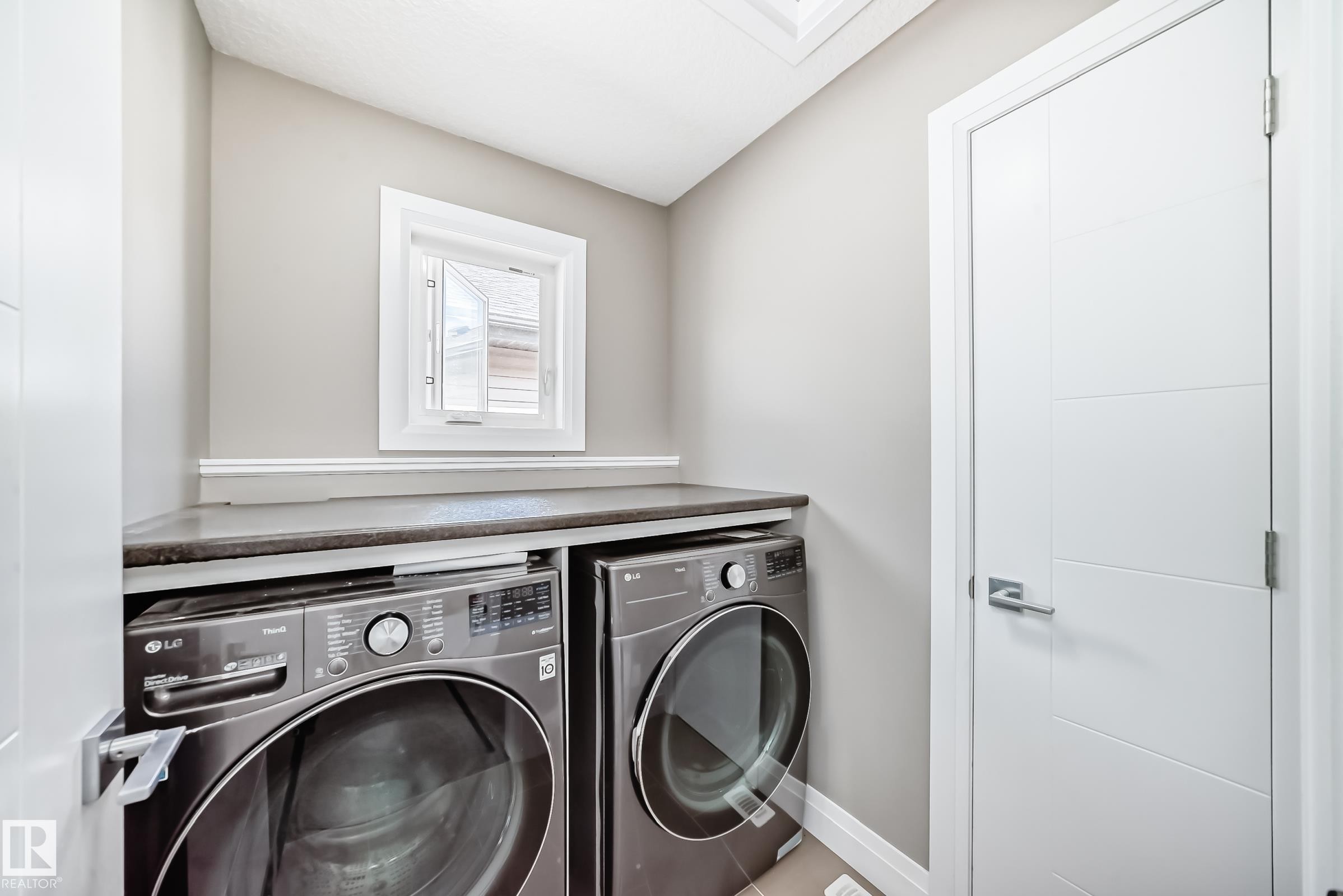 Dedicated laundry area featuring a built-in countertop, light neutral wall paint, and white trim - 4155 Charles Link, Edmonton, AB - Indoor Photo Showing Laundry Room