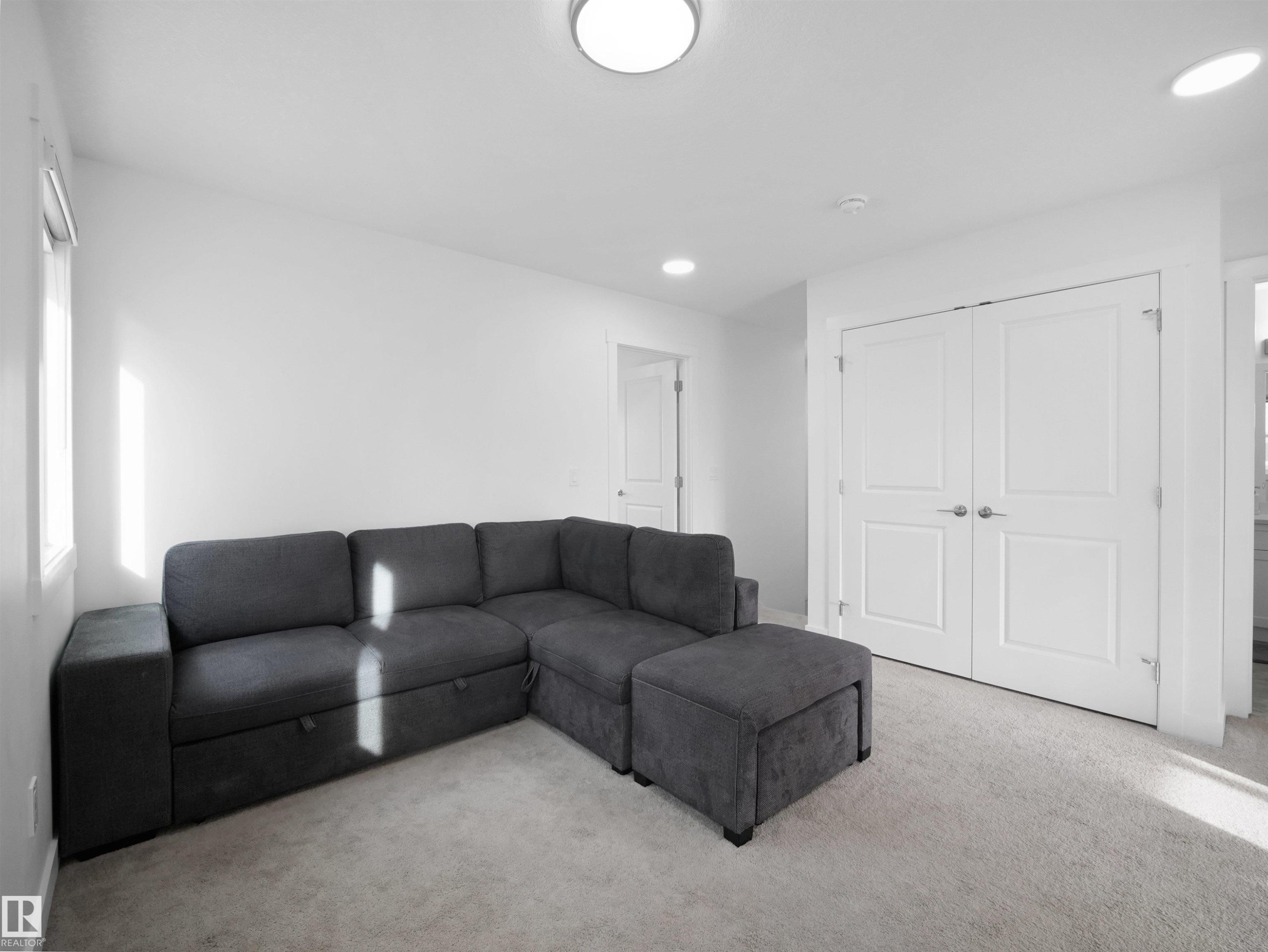 Carpeted room featuring white walls, a window with a roller shade, recessed lighting, and a flush-mount ceiling light - 30 Hope Cm, Spruce Grove, AB - Indoor Photo Showing Living Room