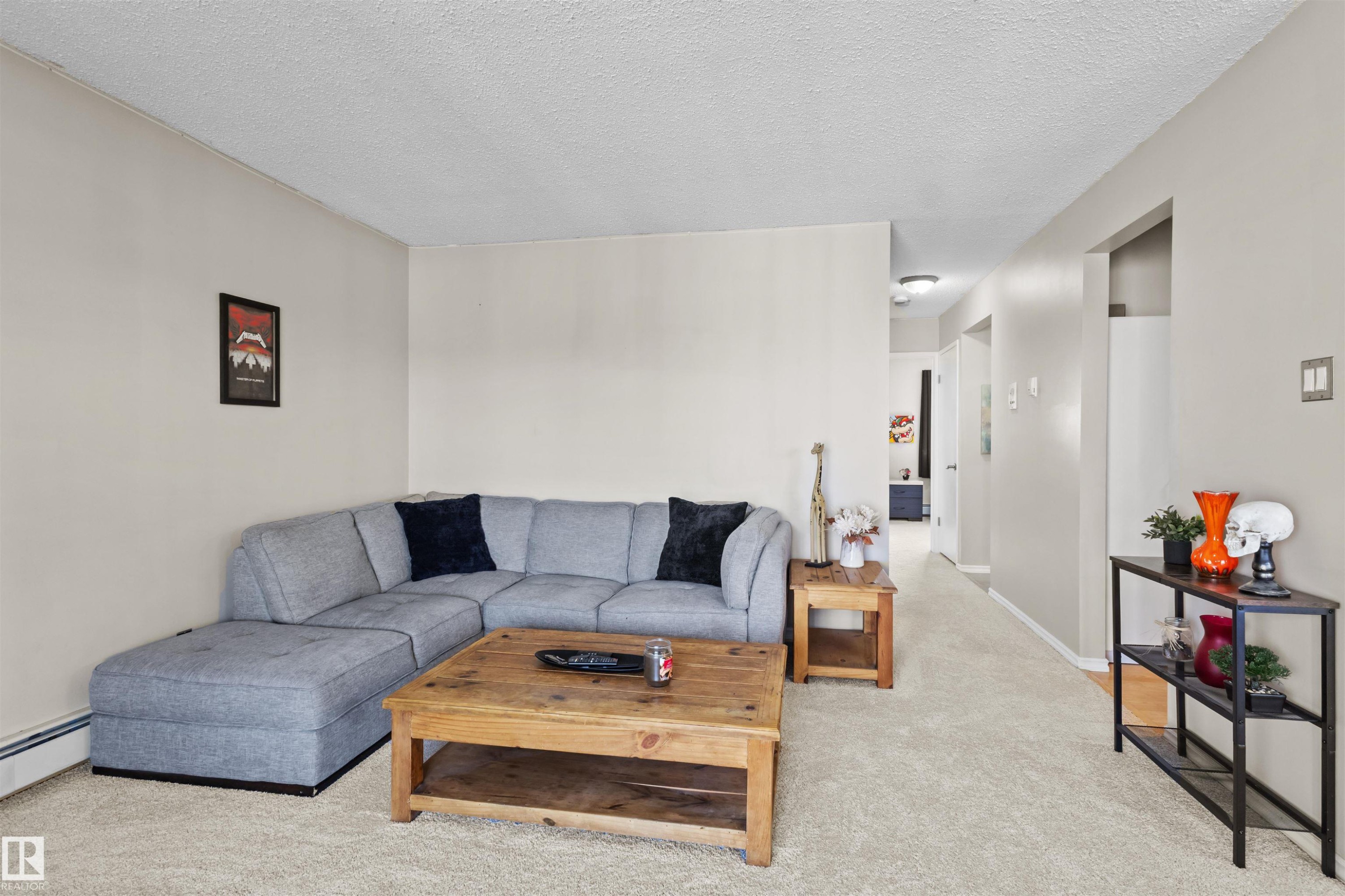 Spacious room featuring neutral wall tones, textured ceiling, and light-toned carpeting - 6 3803 76 Street, Edmonton, AB - Indoor Photo Showing Living Room