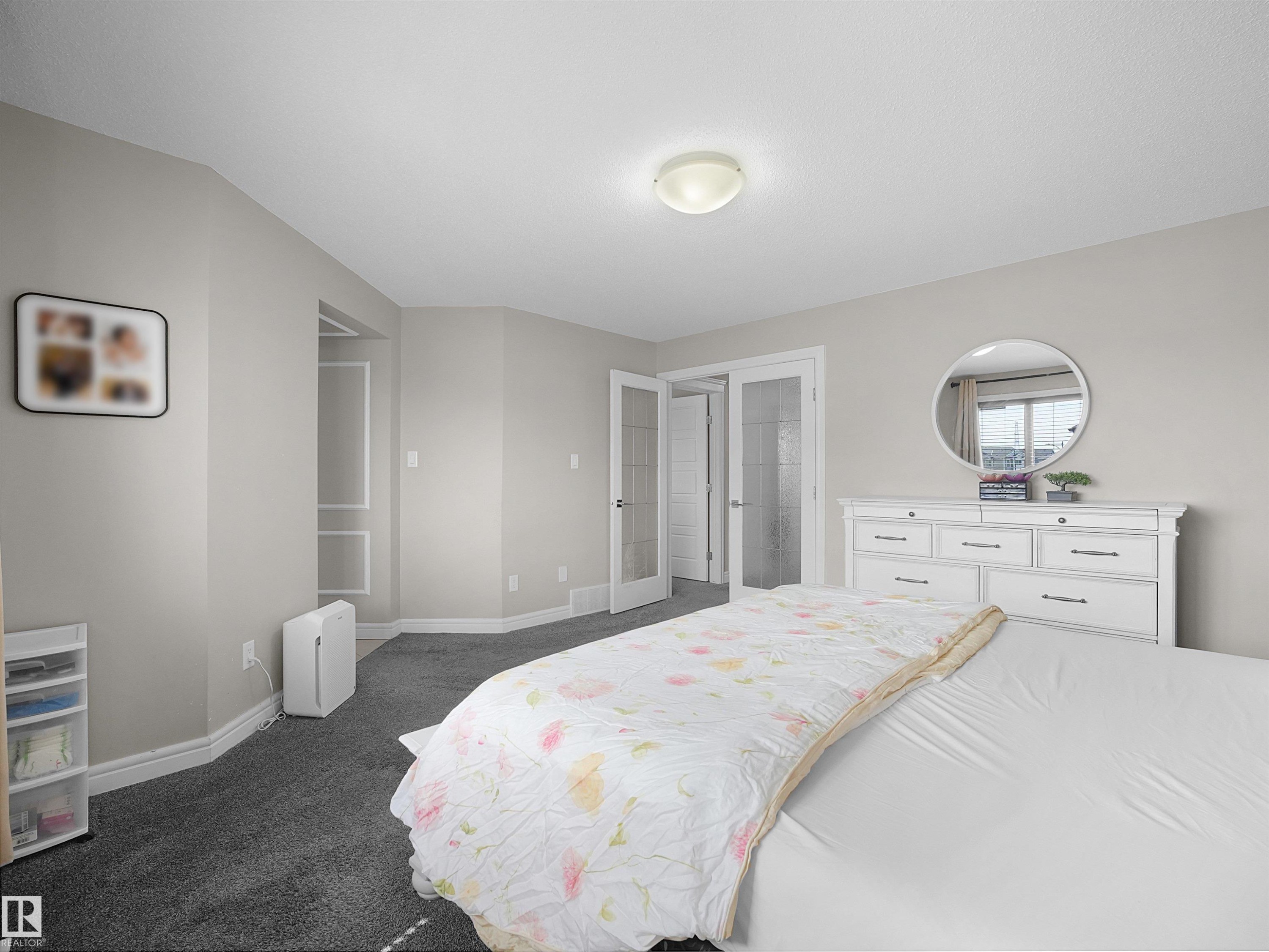 Spacious bedroom featuring neutral wall tones, dark grey carpeting, and white baseboards - 3247 15 Avenue Nw, Edmonton, AB - Indoor Photo Showing Bedroom