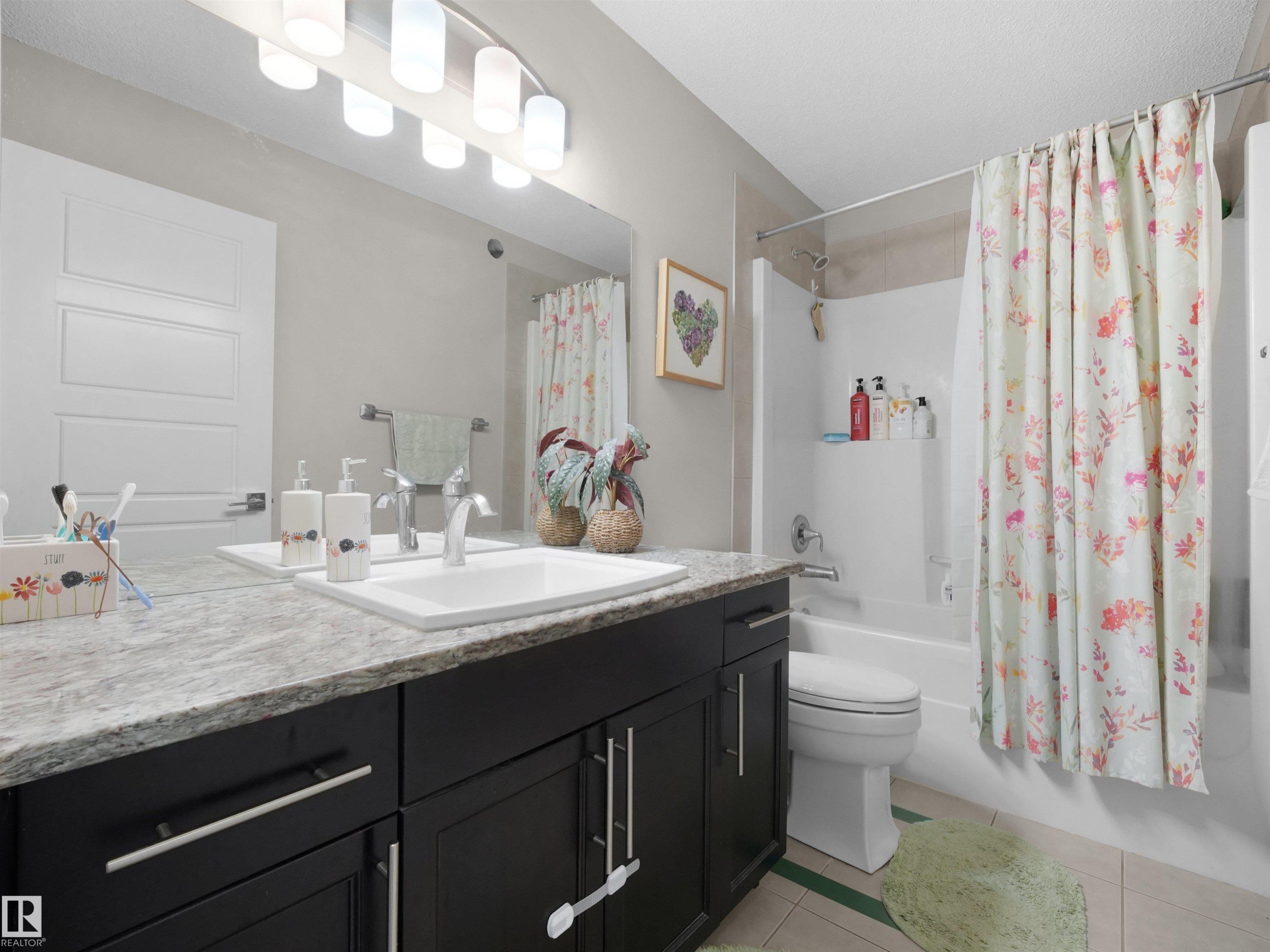 Bathroom featuring a single vanity with dark cabinetry, a light-toned countertop, and an undermount sink - 3247 15 Avenue Nw, Edmonton, AB - Indoor Photo Showing Bathroom